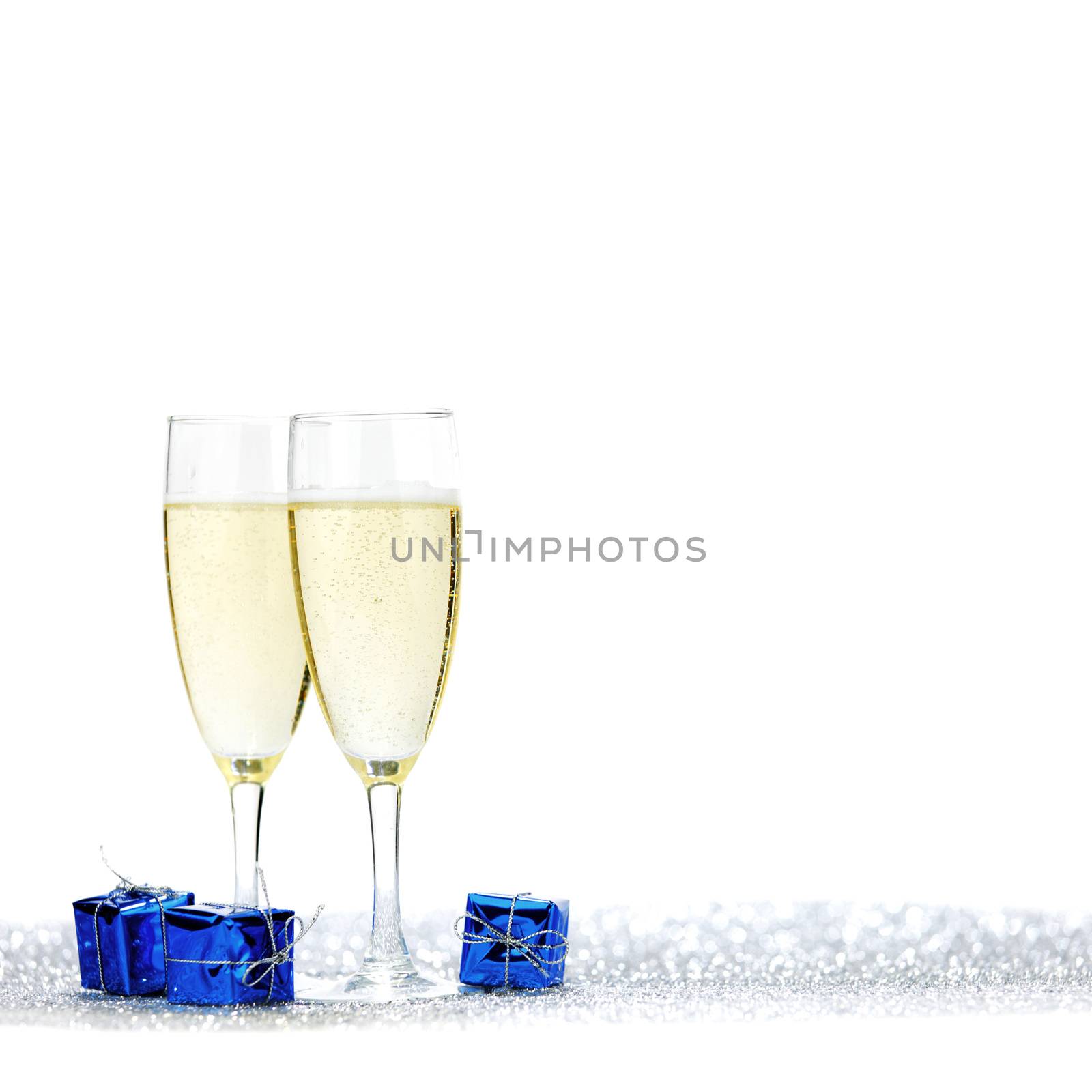 Glasses of champagne and blue gifts isolated on white