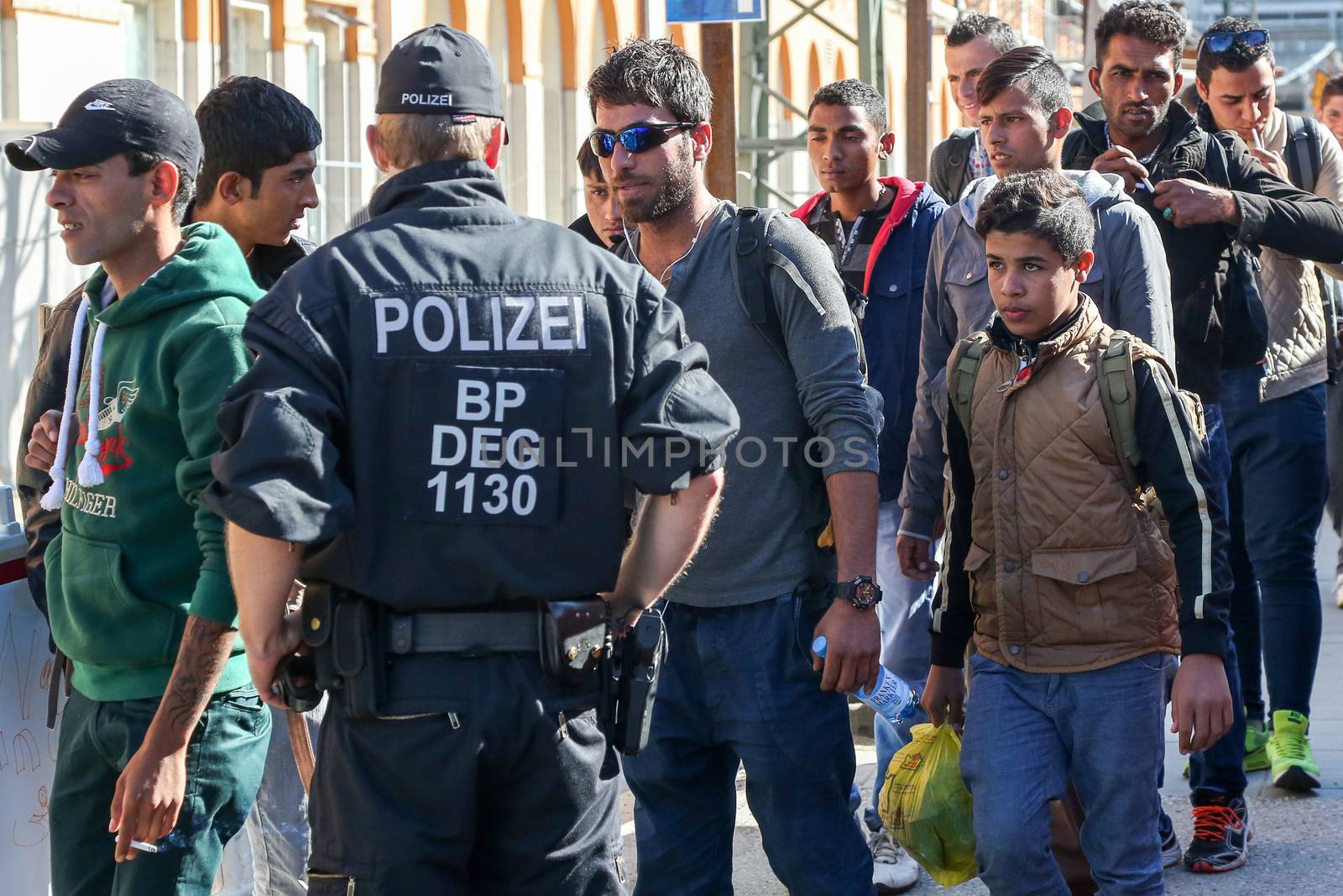 GERMANY, Passau: Security officials stand guard as refugees wait in long queues in the border town of Passau, Germany on September 21, 2015 amid the reintroduction of border controls in Germany, Austria, and a number of other EU countries, aimed at slowing the flow of refugees from war-torn Syria.