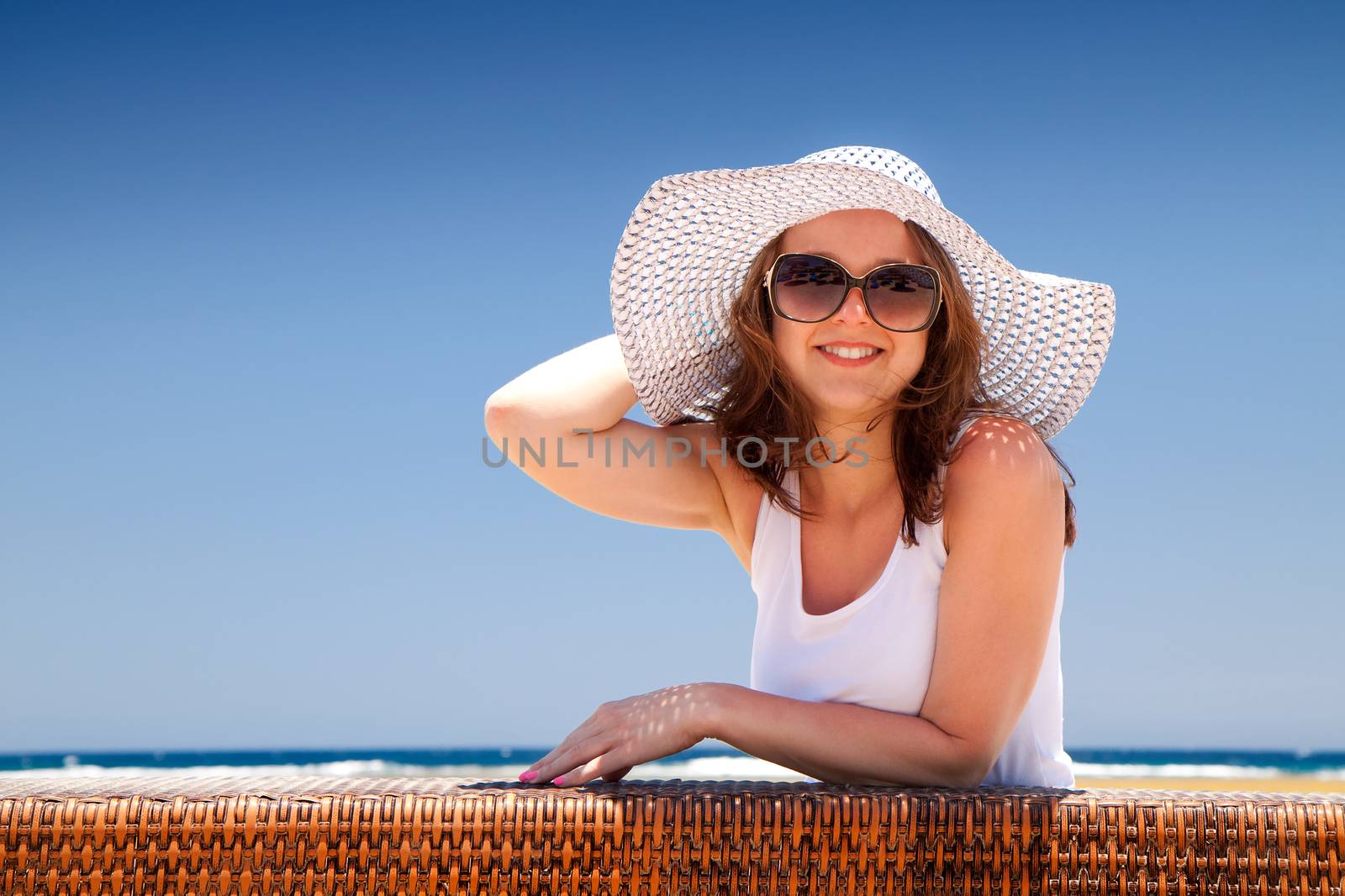 The young beautiful woman in a hat on holidays, on a sunny beach