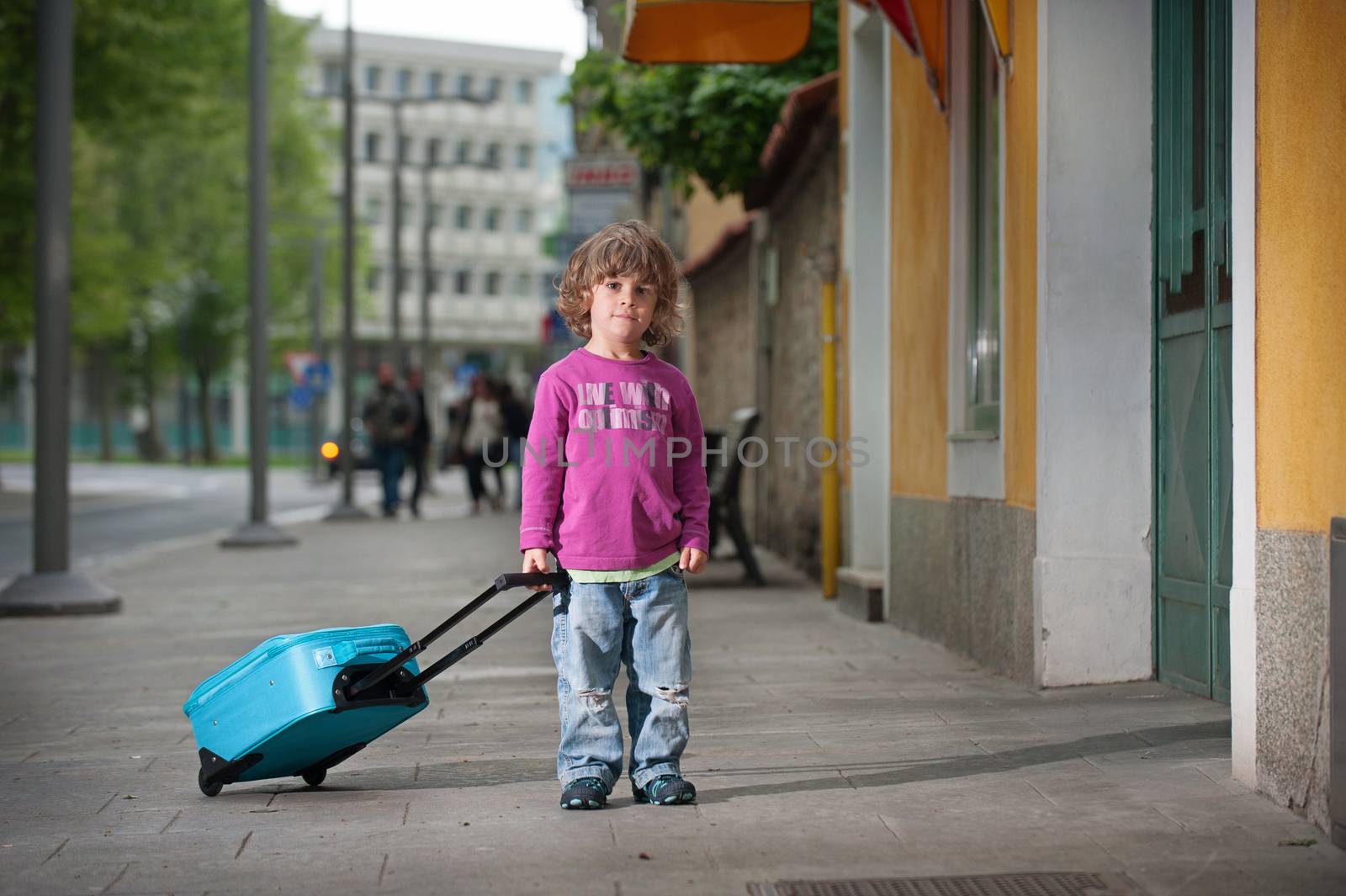 Cute little boy with a luggage bag on the street. Growing up and becoming independent concept