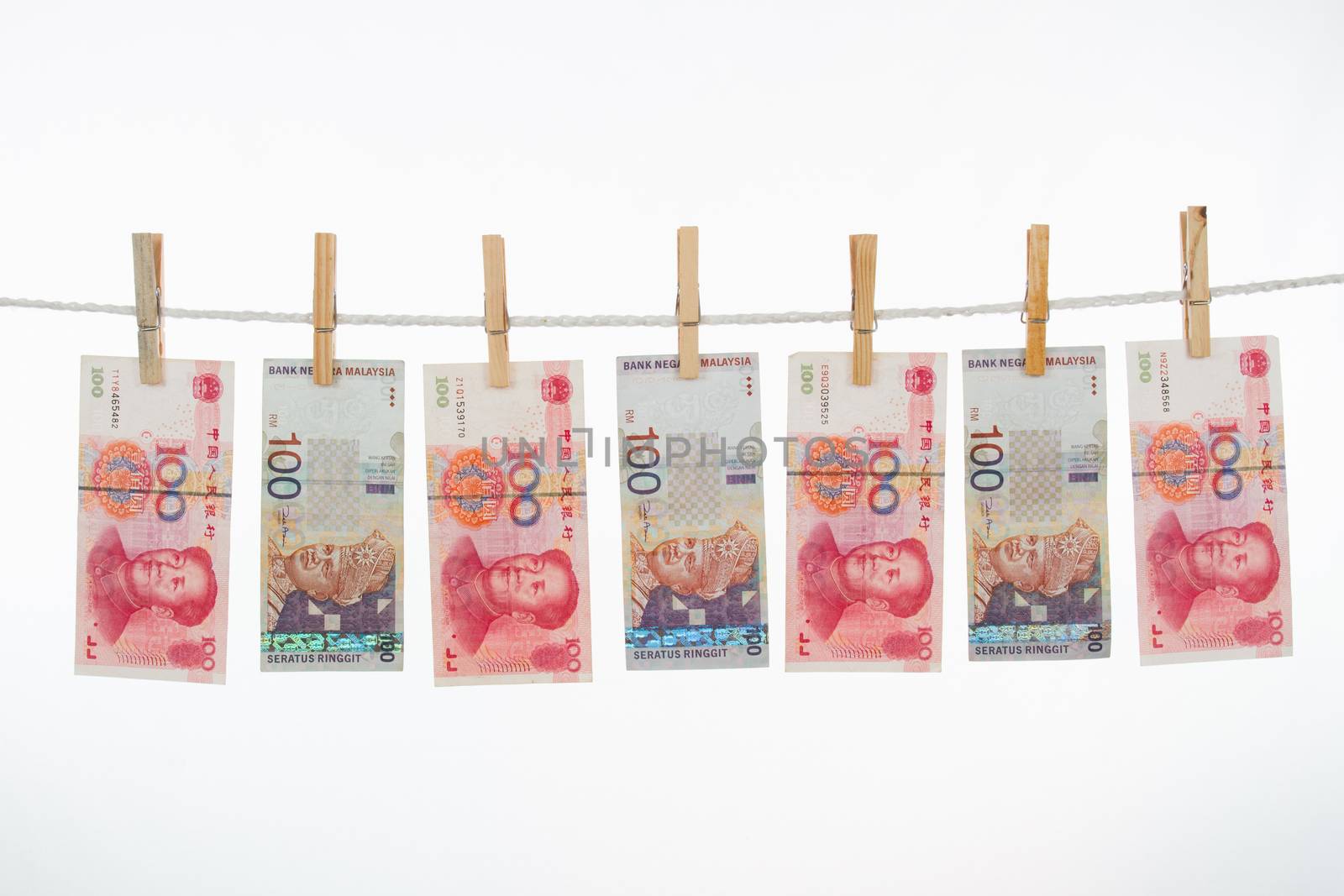 Money laundering concept with China and Malaysia notes on clothesline in plain isolated white background.