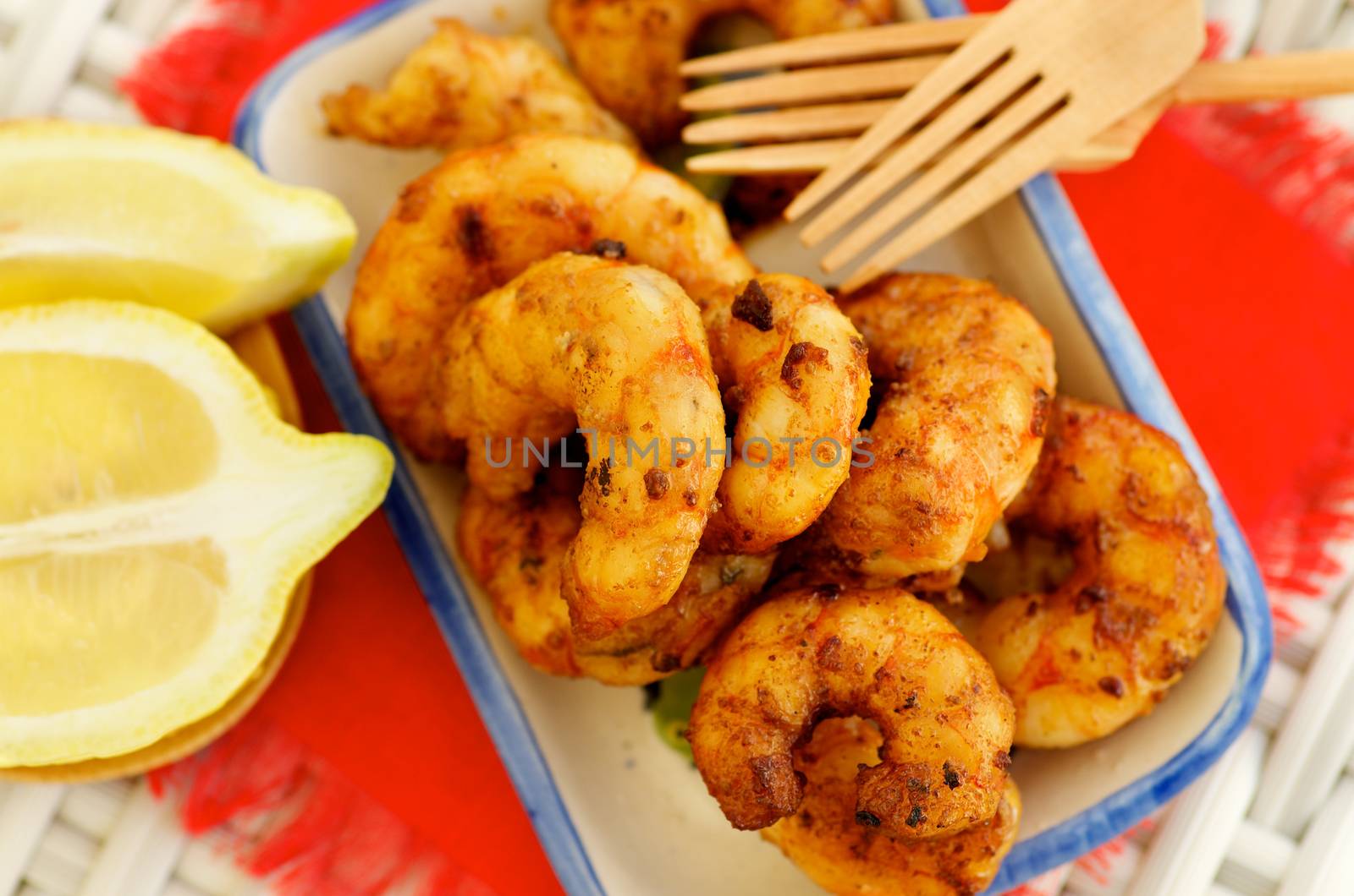 Delicious Grilled Prawns with Sliced Lemon and Wooden Forks closeup on Red Napkin. Selective Focus