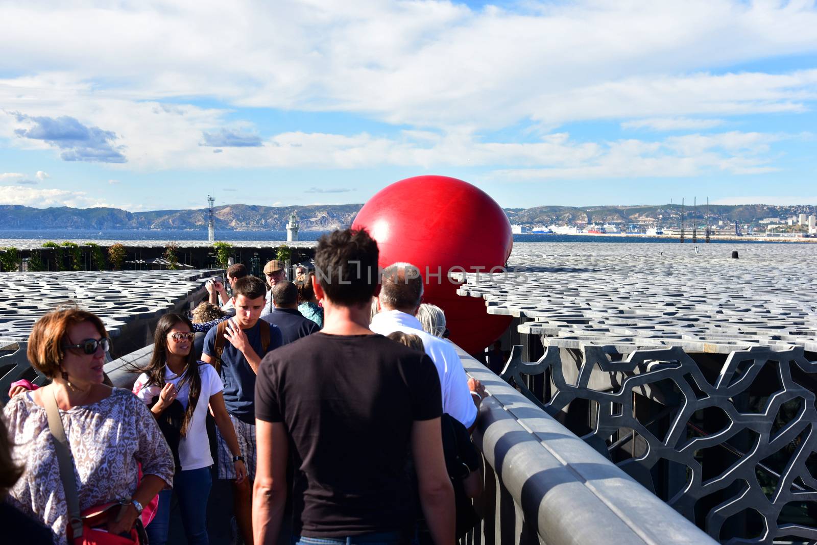 FRANCE, Marseille : This picture taken on September 19, 2015 in Marseille, shows a red ball on the roof of Mucem museum. New York based artist Kurt Perschke's RedBall project stopped off in Marseille between September 19 and 25, 2015. The project involves installing a five meter wide red ball in different places from town to town. 