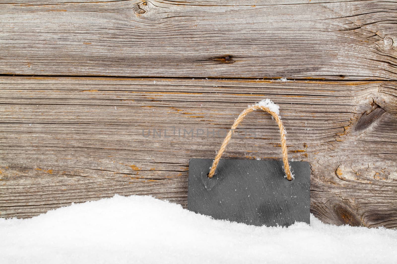 Black board of slate on old rustic wooden background, with snow by motorolka
