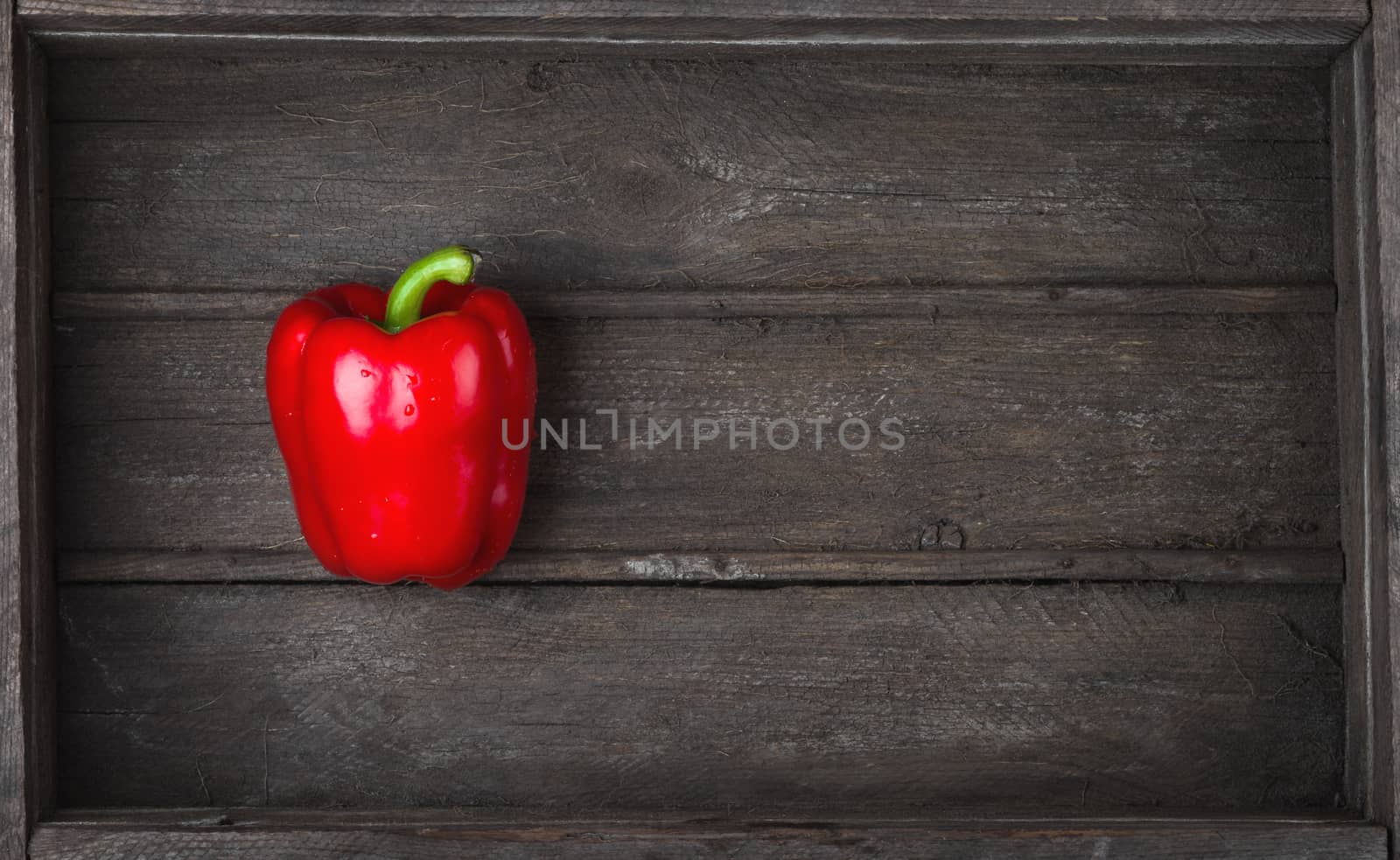 sweet red bell pepper in old wooden box, closeup top view
