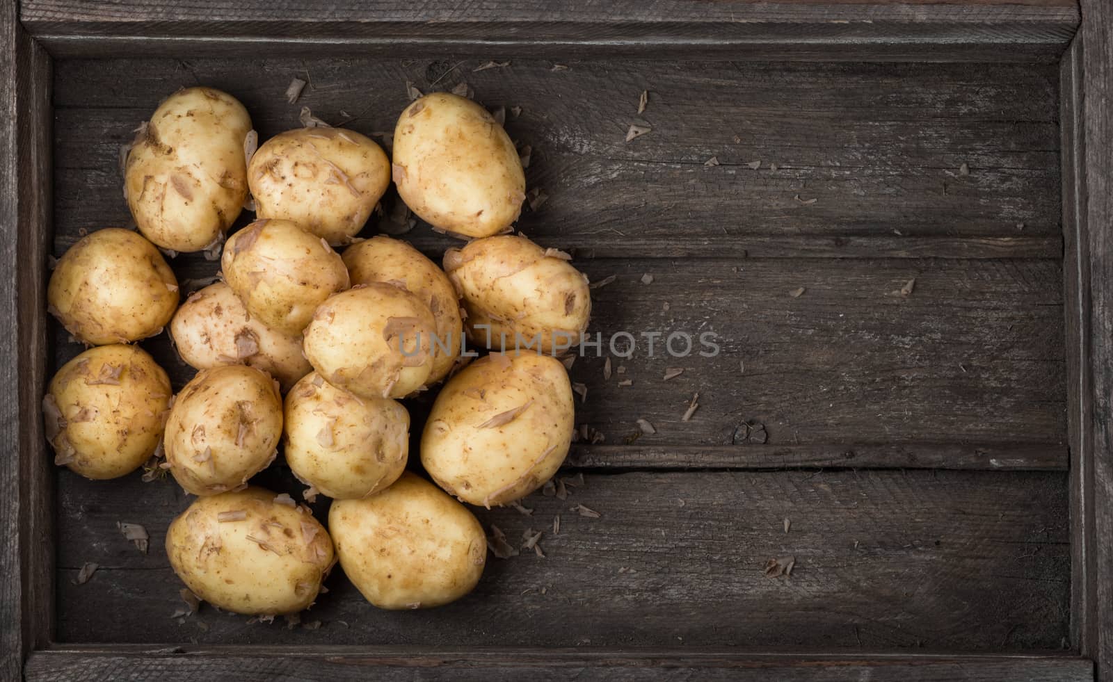 pile of raw new potatoes in an old wooden box top view. Harvest