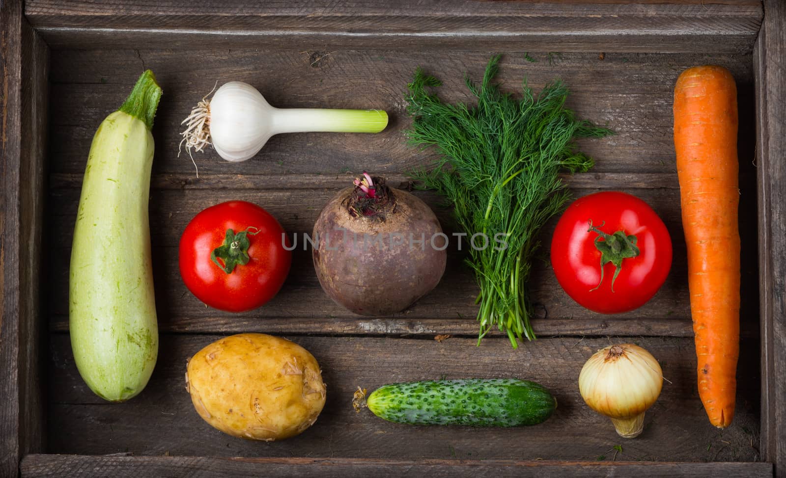 Food for raw foodists. Set of different fresh raw vegetables in an old wooden box: garlic, zucchini, tomato, carrot, cucumber, potatoes, beets, onions, dill. Harvest. Ingredients for vegetable dishes