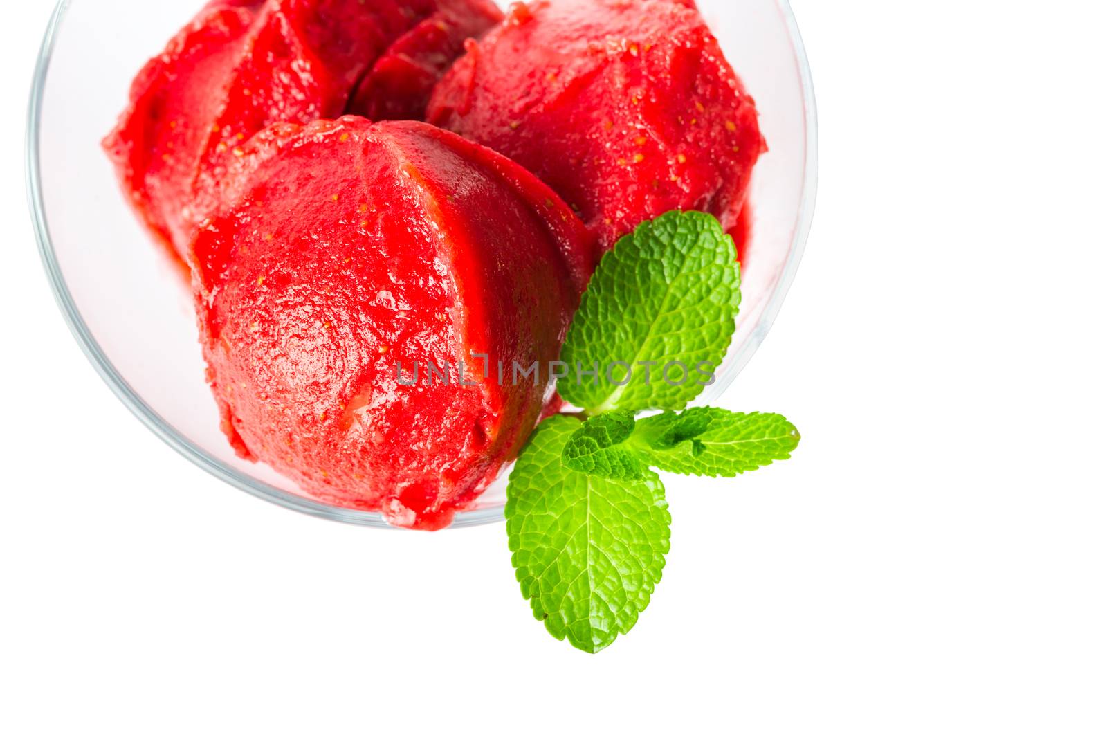 Strawberry sorbet in a glass bowl and a sprig of fresh mint, top view close up isolated on a white background