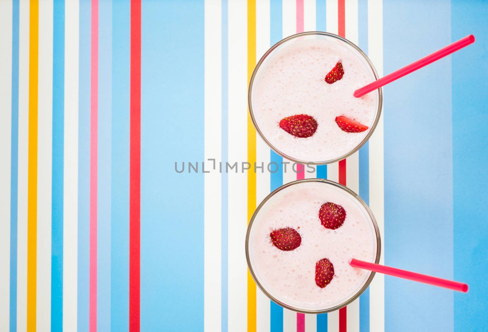 Delicious, nutritious and healthy fresh strawberry yogurt in glass beakers and drinking straws on bright background
