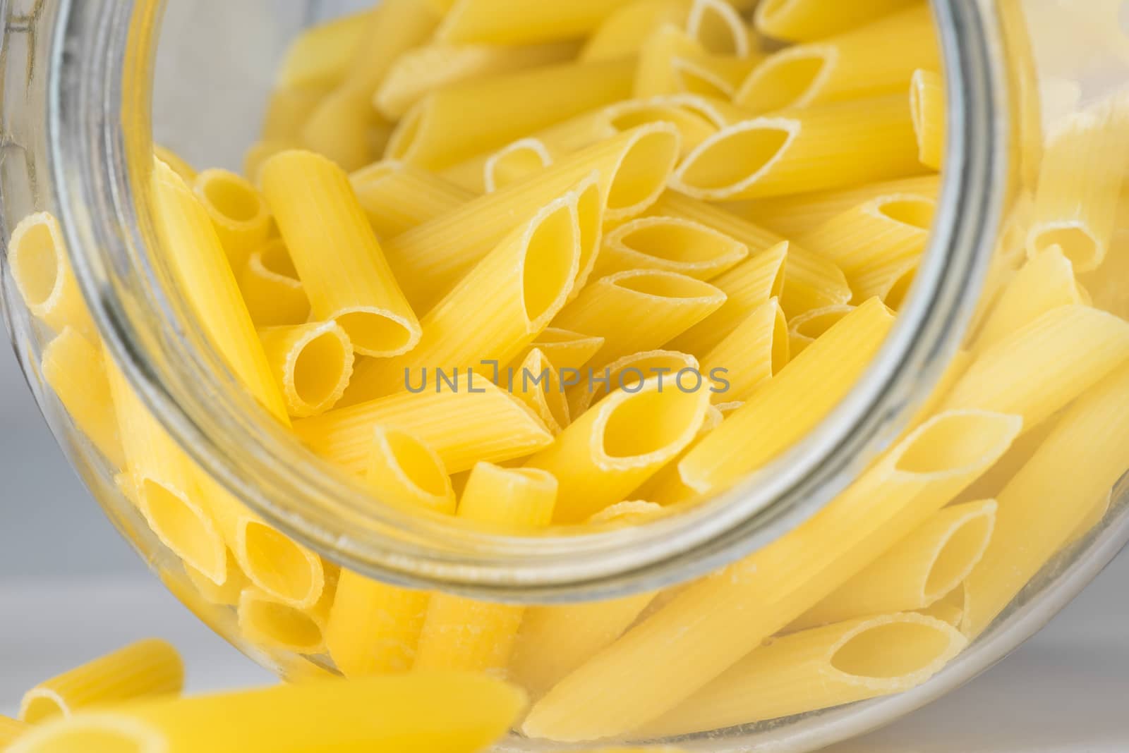 Italian Penne Rigate Macaroni Pasta raw food, a glass jar, close up