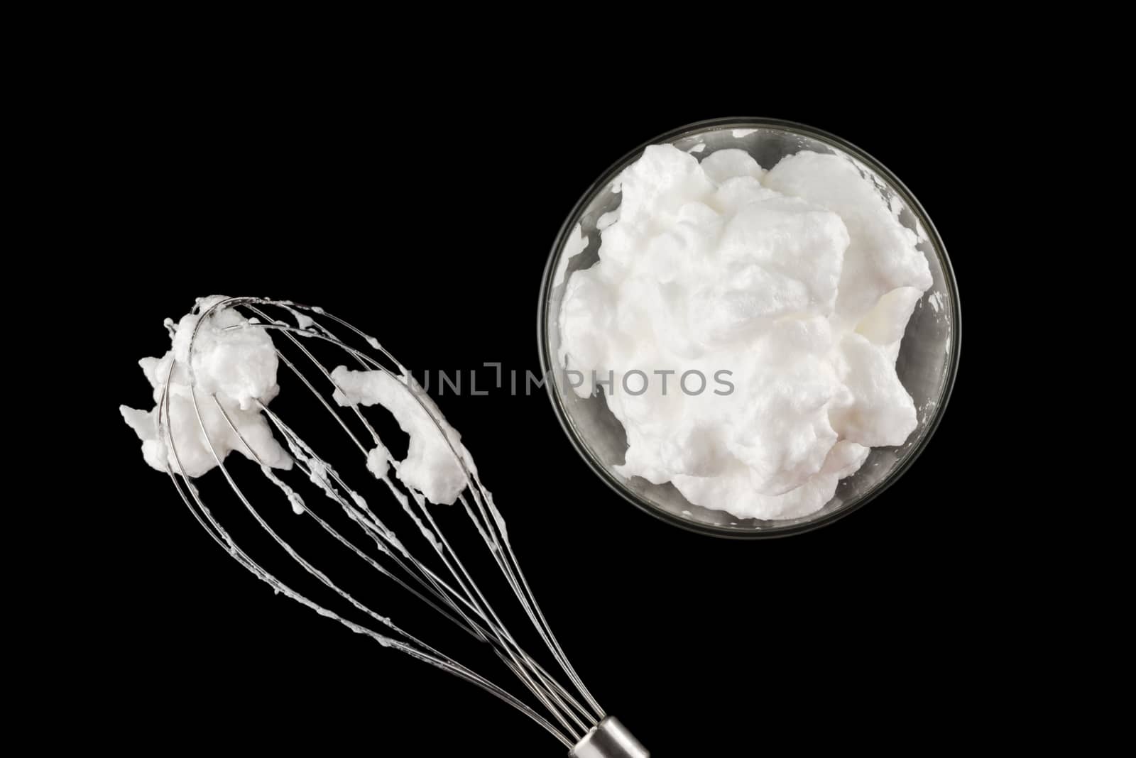 beaten eggs whites  for cream with whisk isolated on black background, top view 