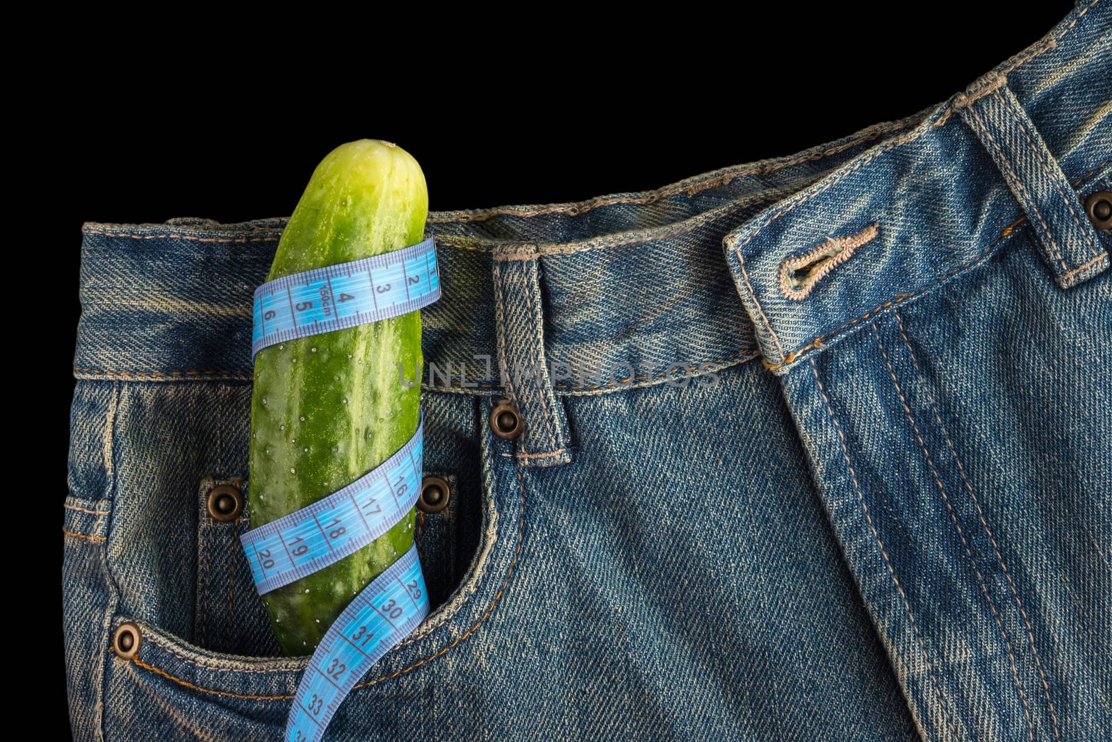 Big cucumber like the penis, men's jeans  and centimeter, on dark background, potency concept