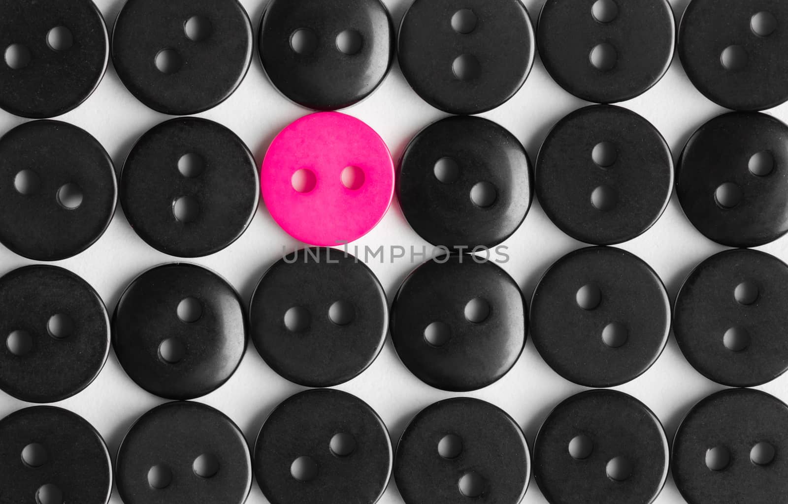 several rows of black buttons on a white background, among them the one bright pink, stands out concept, to be bright, life style