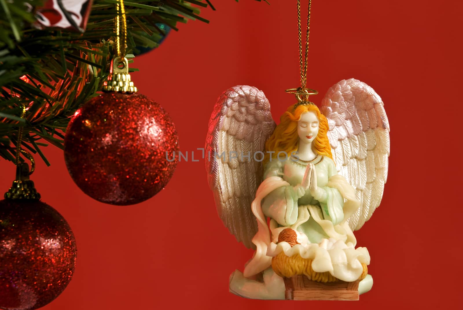 Horizontal shot of a beautiful angel ornament hanging on the Christmas tree and shot on red background.