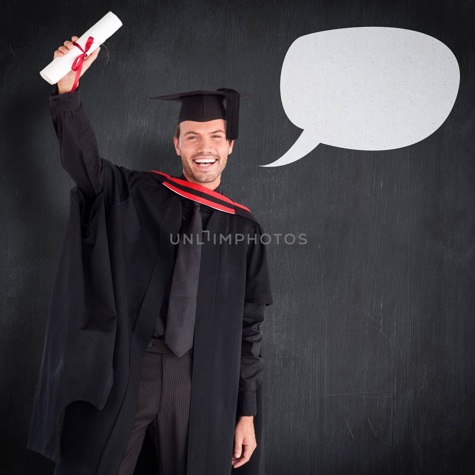 Smiling handsome boy showing his diploma to the camera  against blackboard