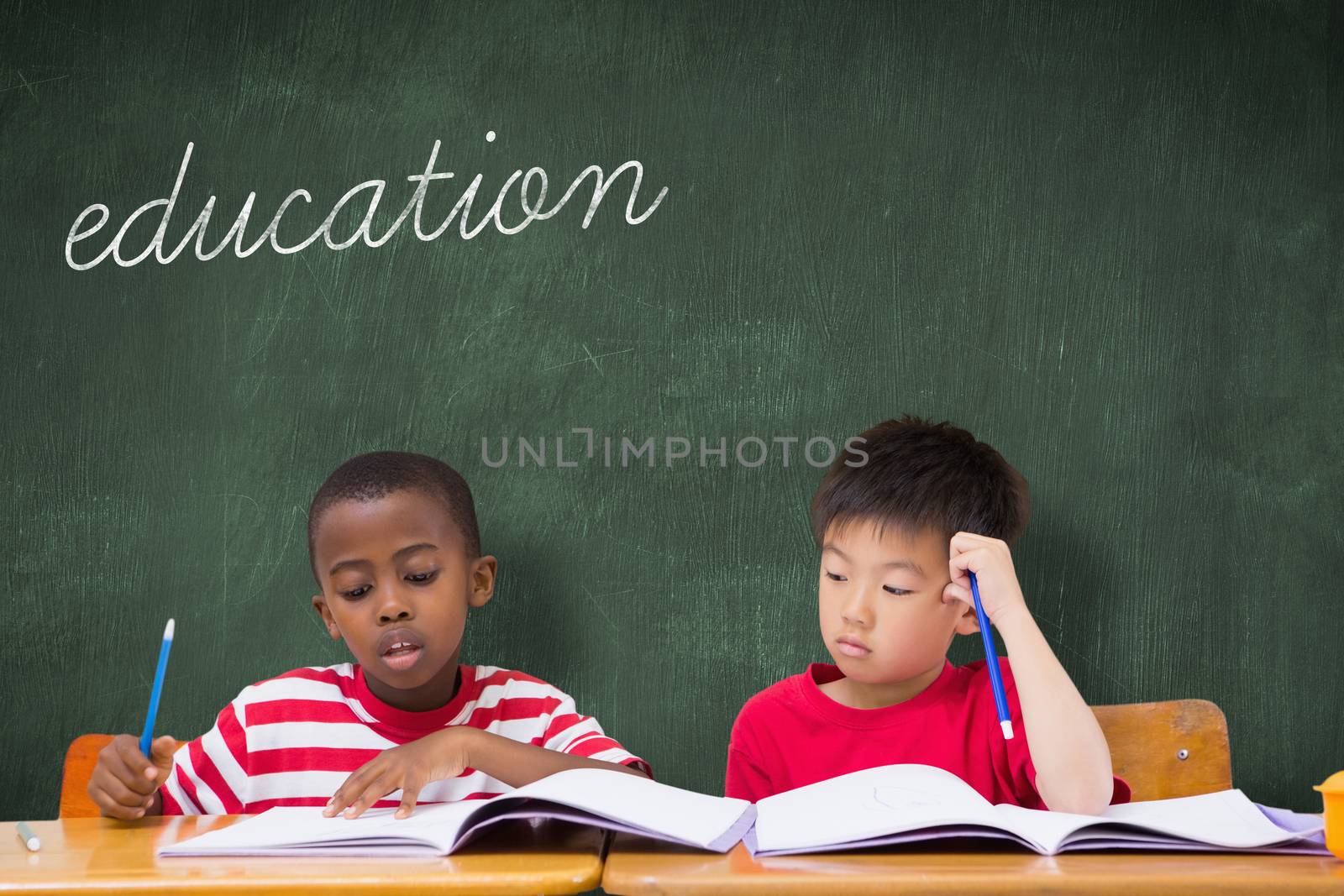 The word education and cute pupils writing at desk in classroom against green chalkboard