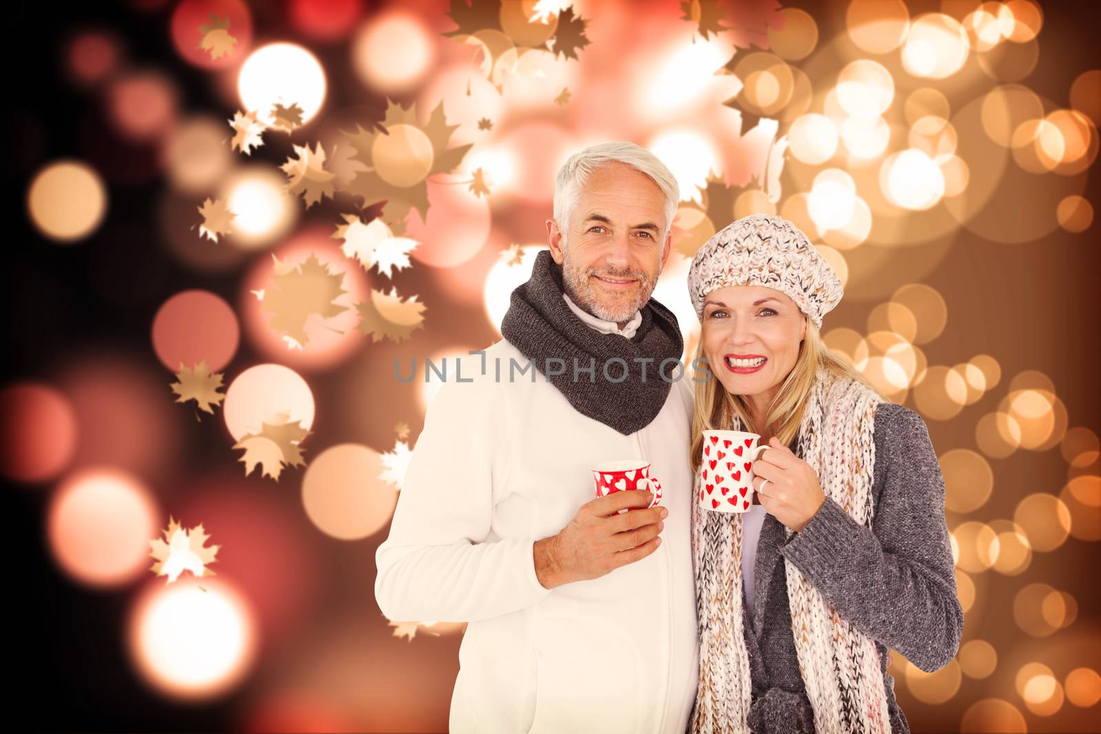 Portrait of happy couple drinking hot coffee against autumnal leaf pattern