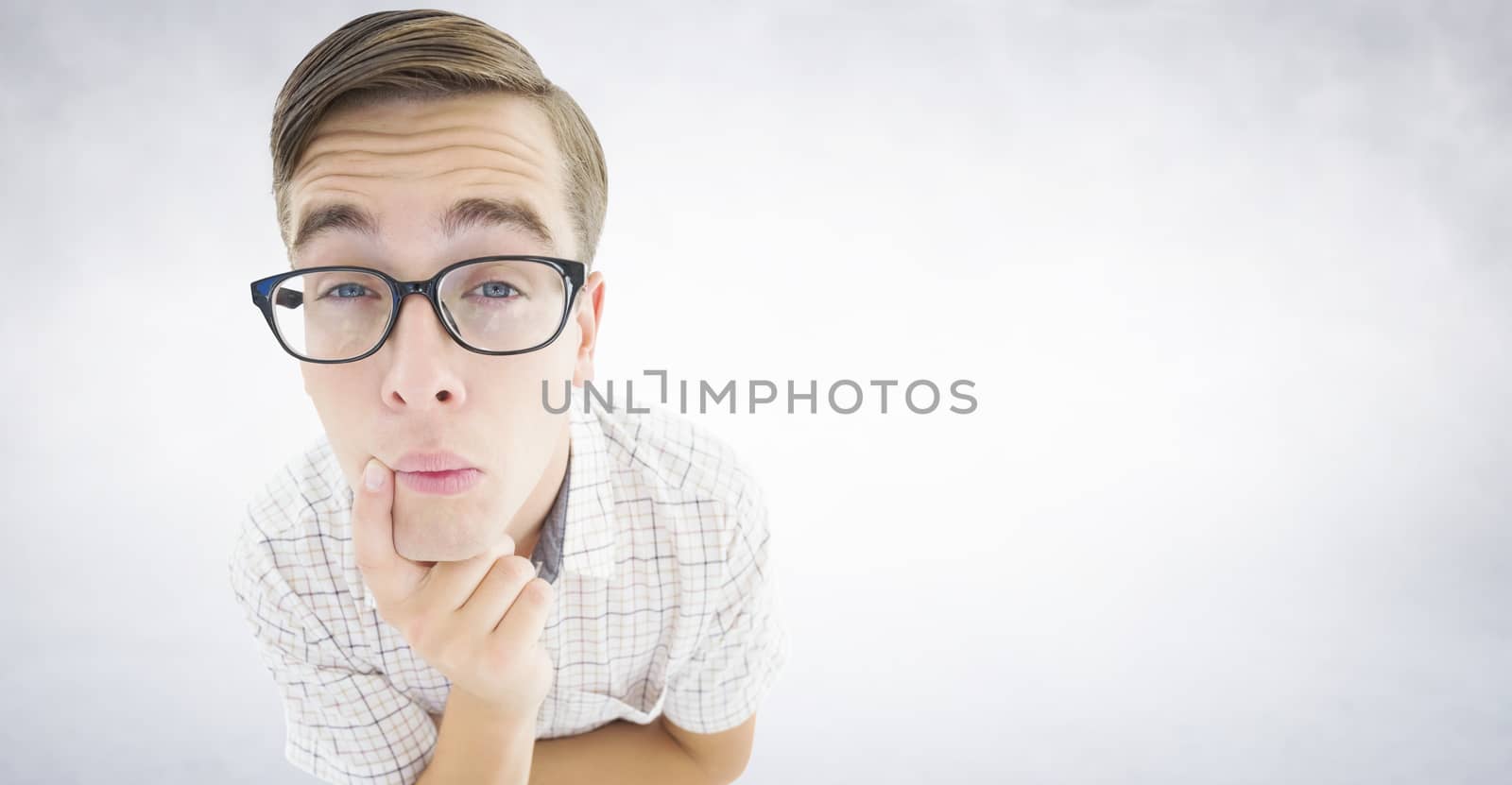 Geeky hipster thinking with hand on chin against white wall