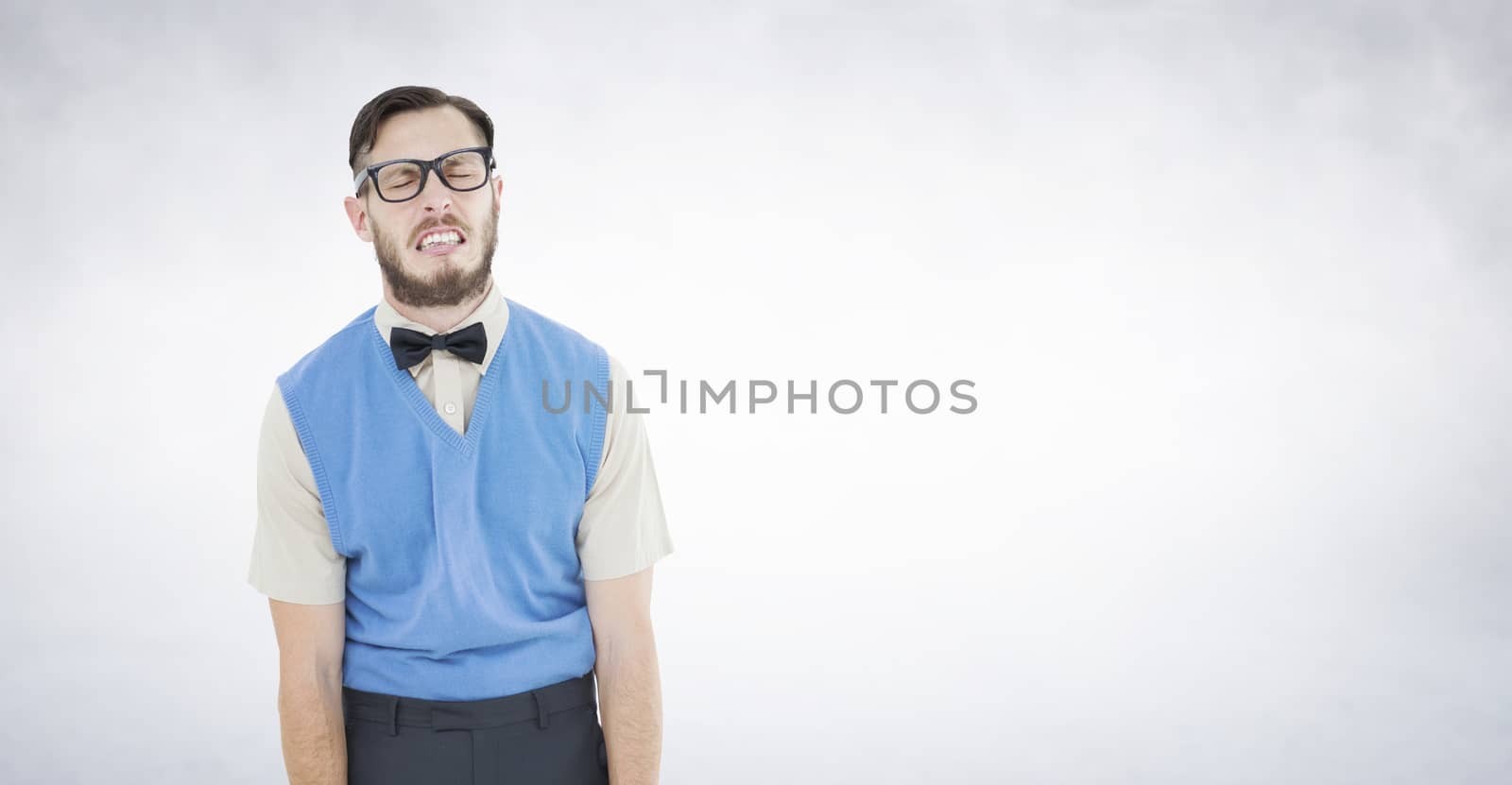 Geeky hipster pulling a silly face against white wall