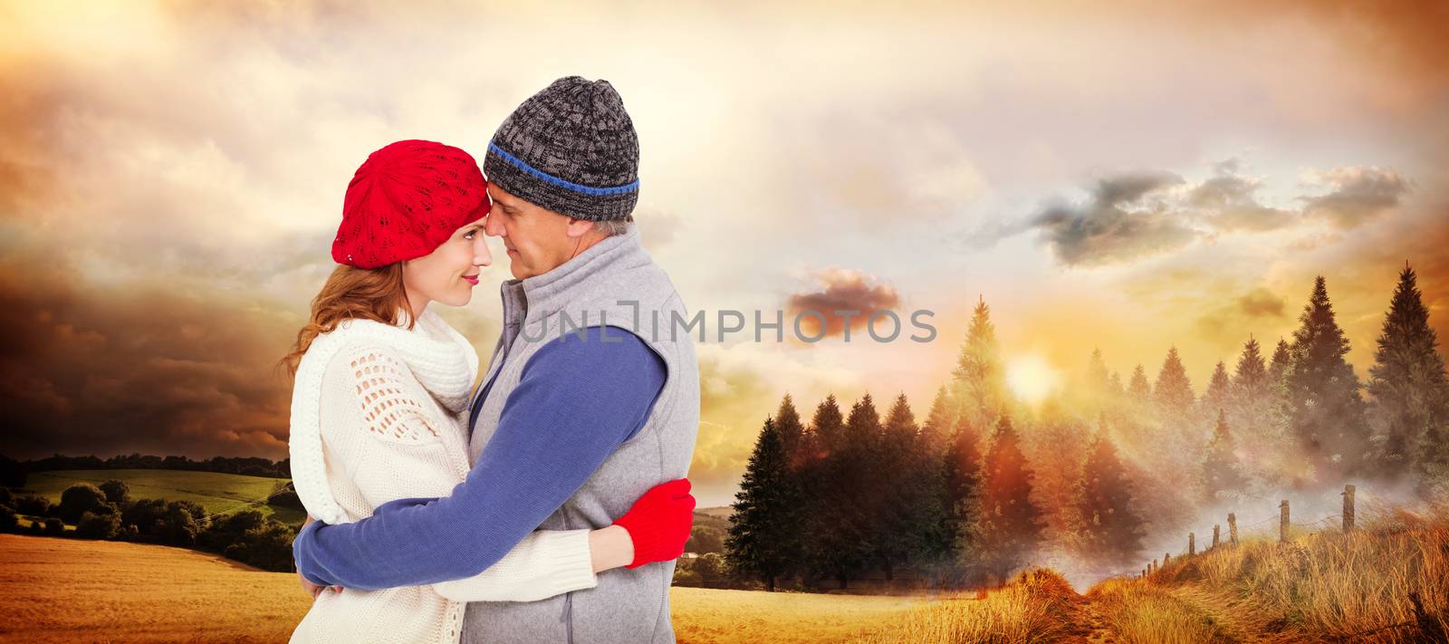 Happy couple in warm clothing hugging against country scene