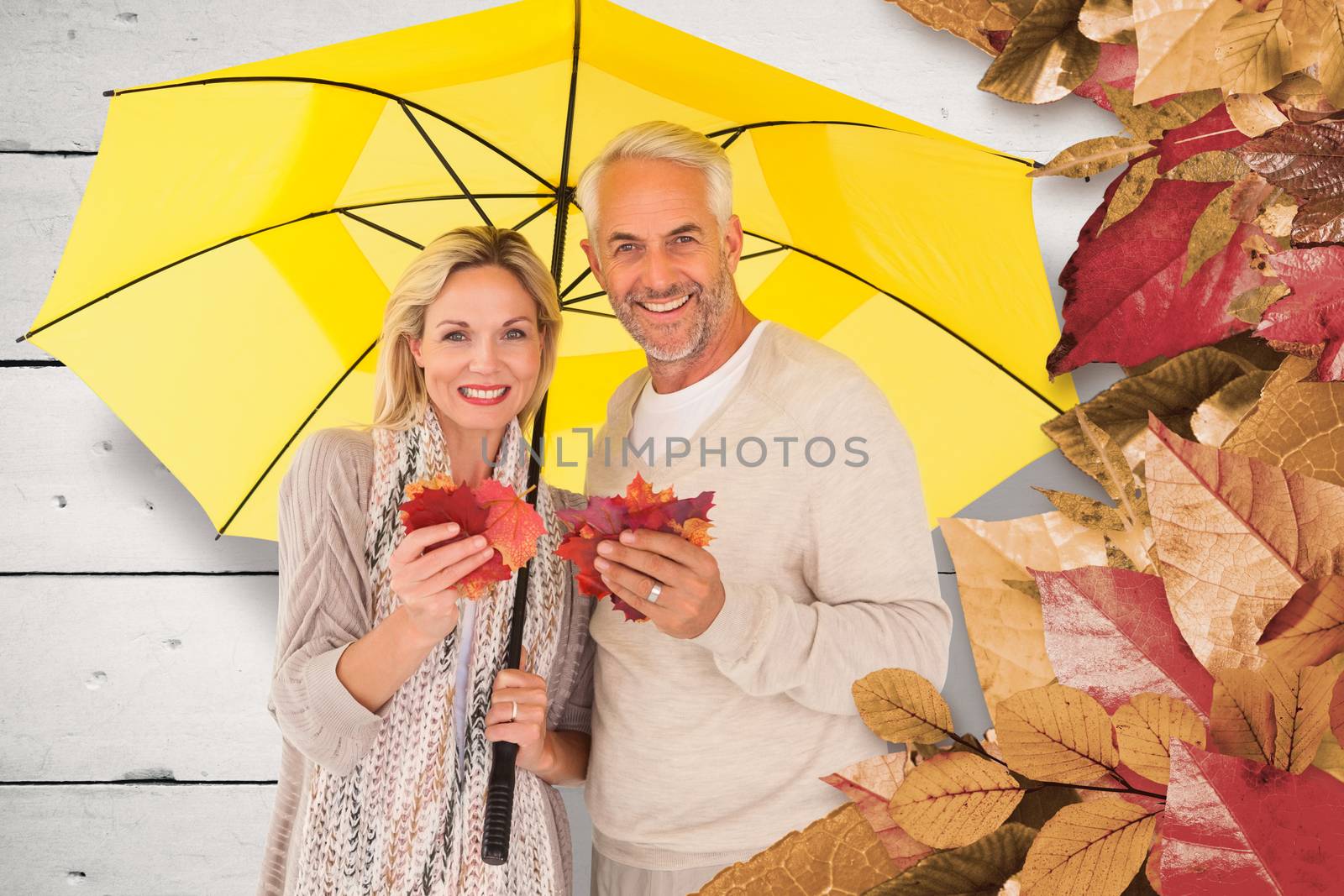 Portrait of happy couple under yellow umbrella against white wood