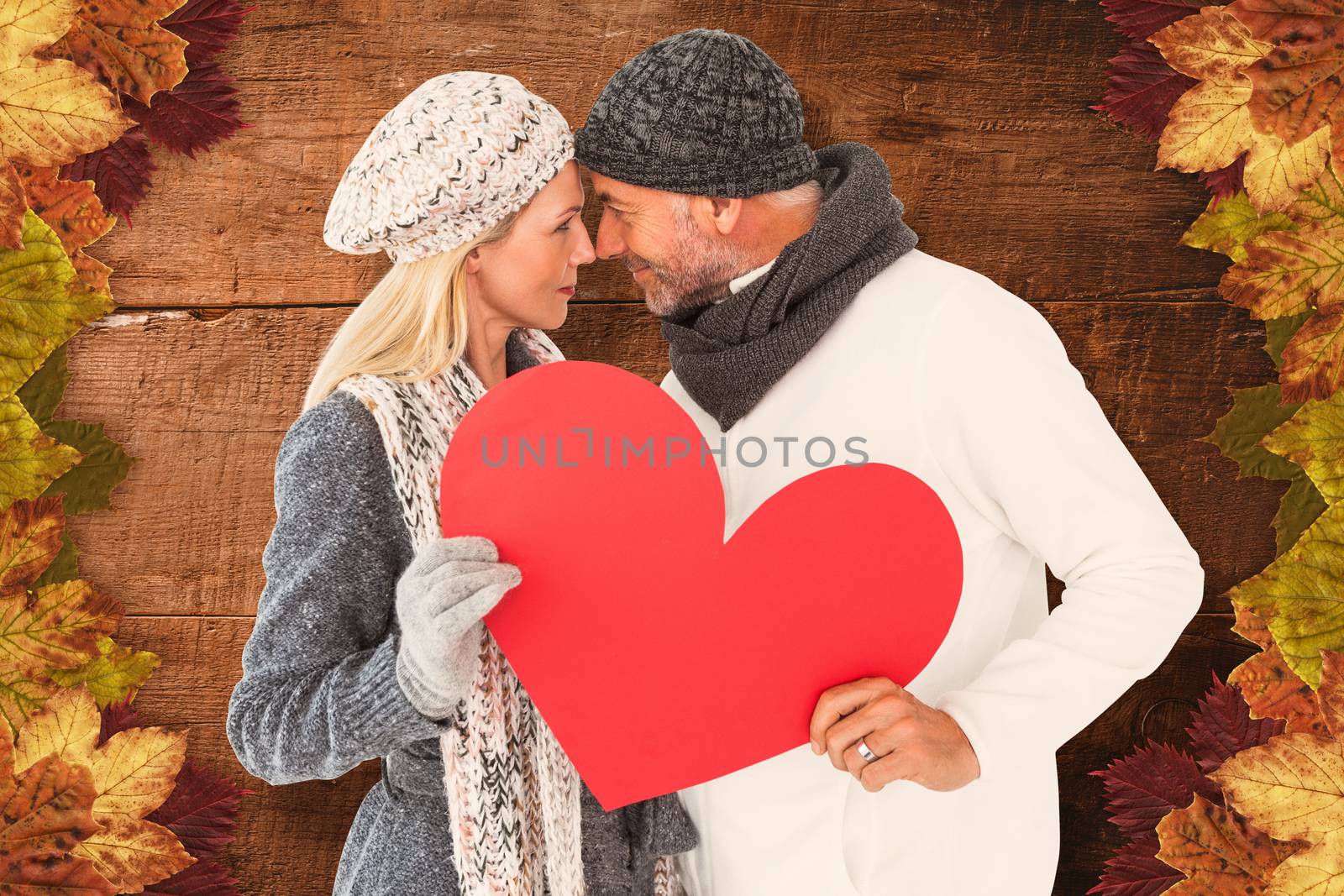 Couple holding heart while looking at each other against overhead of wooden planks