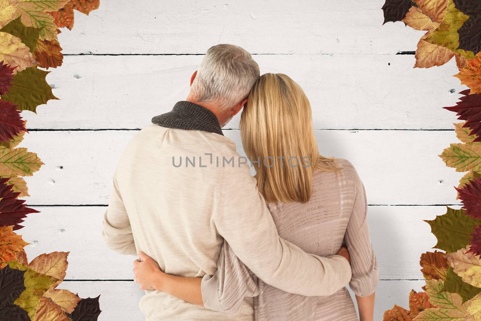 Rear view of couple with arms around against white wood