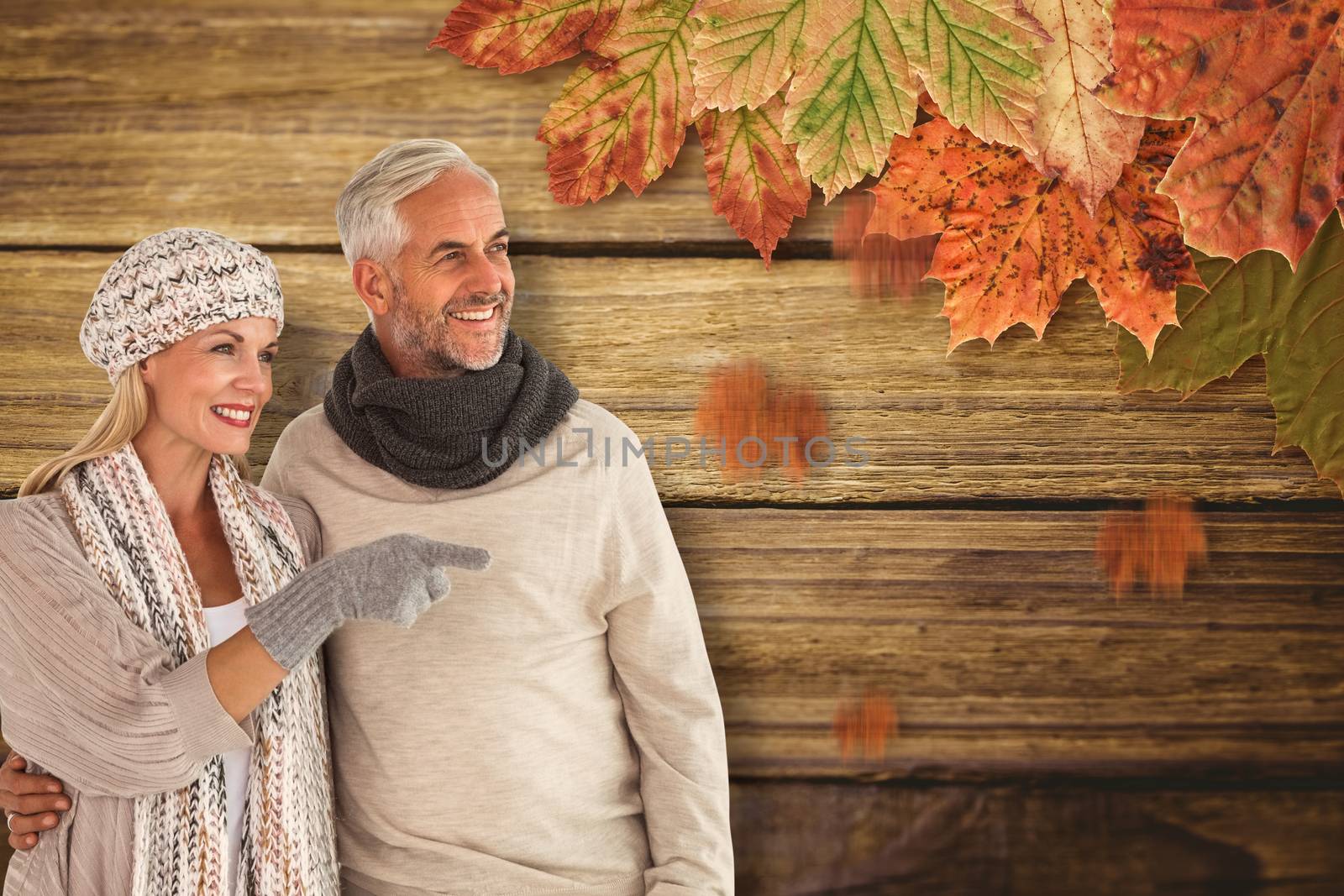 Wife pointing finger while standing besides husband against wooden background