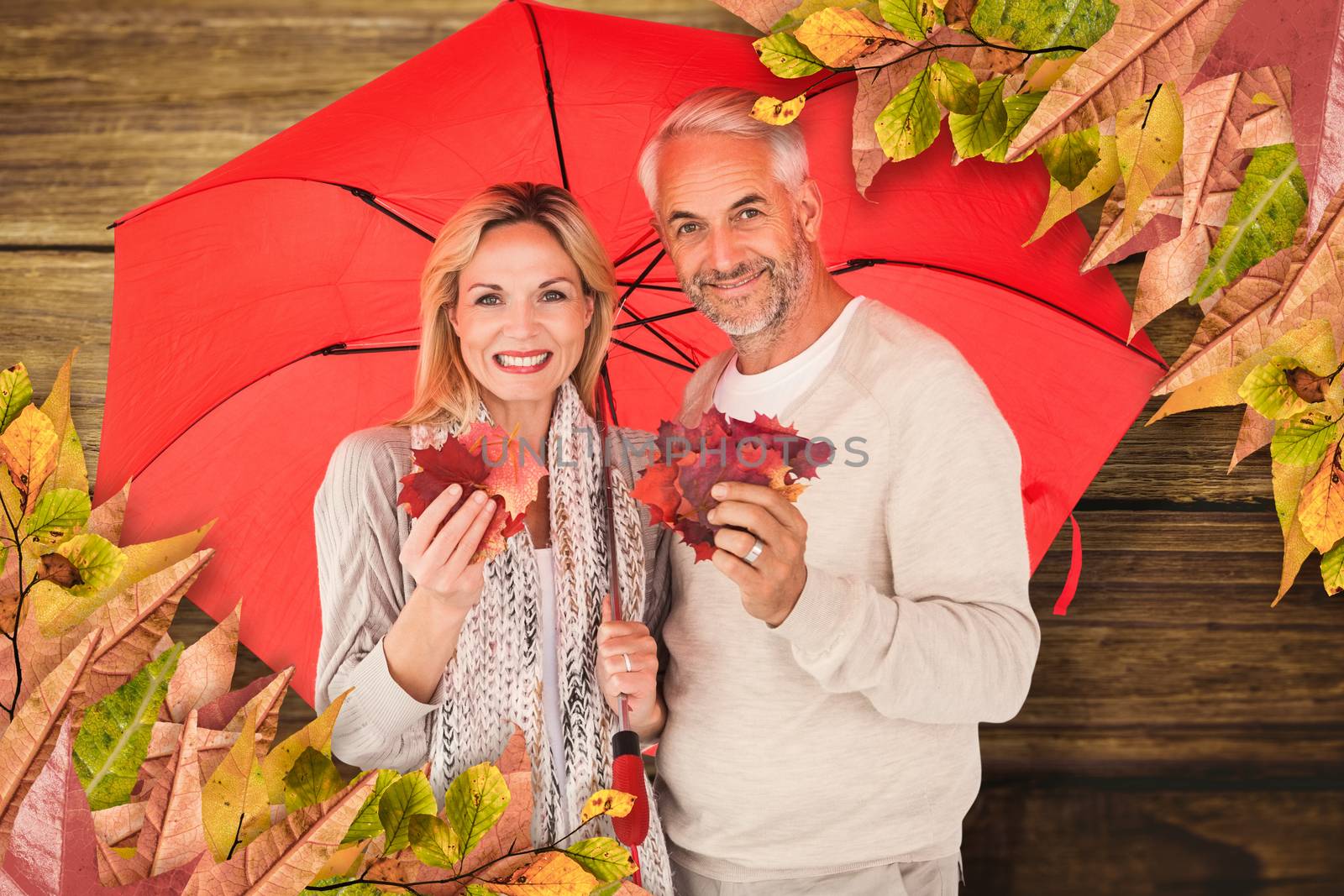 Portrait of happy couple under red umbrella against wooden background