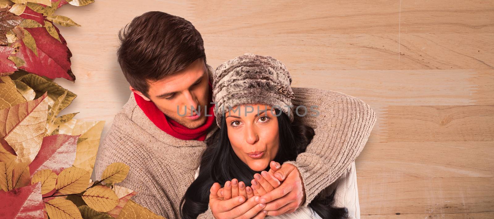 Young couple blowing over hands against bleached wooden planks background