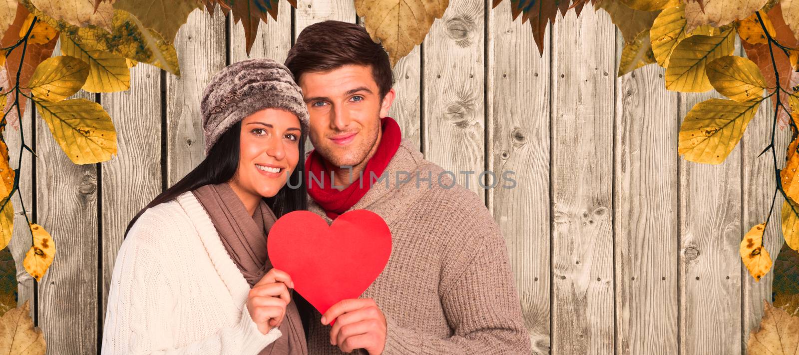 Composite image of young couple smiling holding red heart by Wavebreakmedia