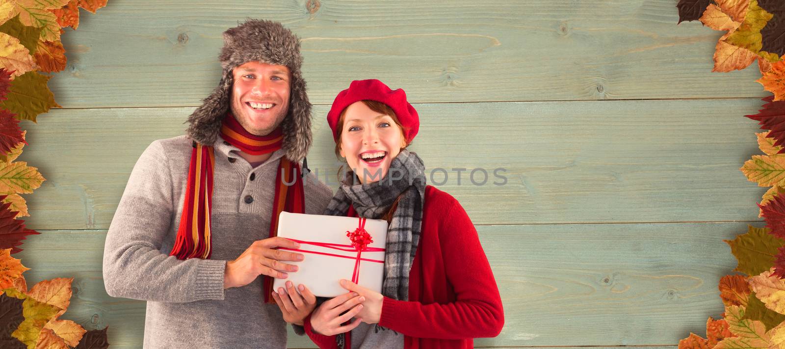 Couple smiling and holding gift against bleached wooden planks background