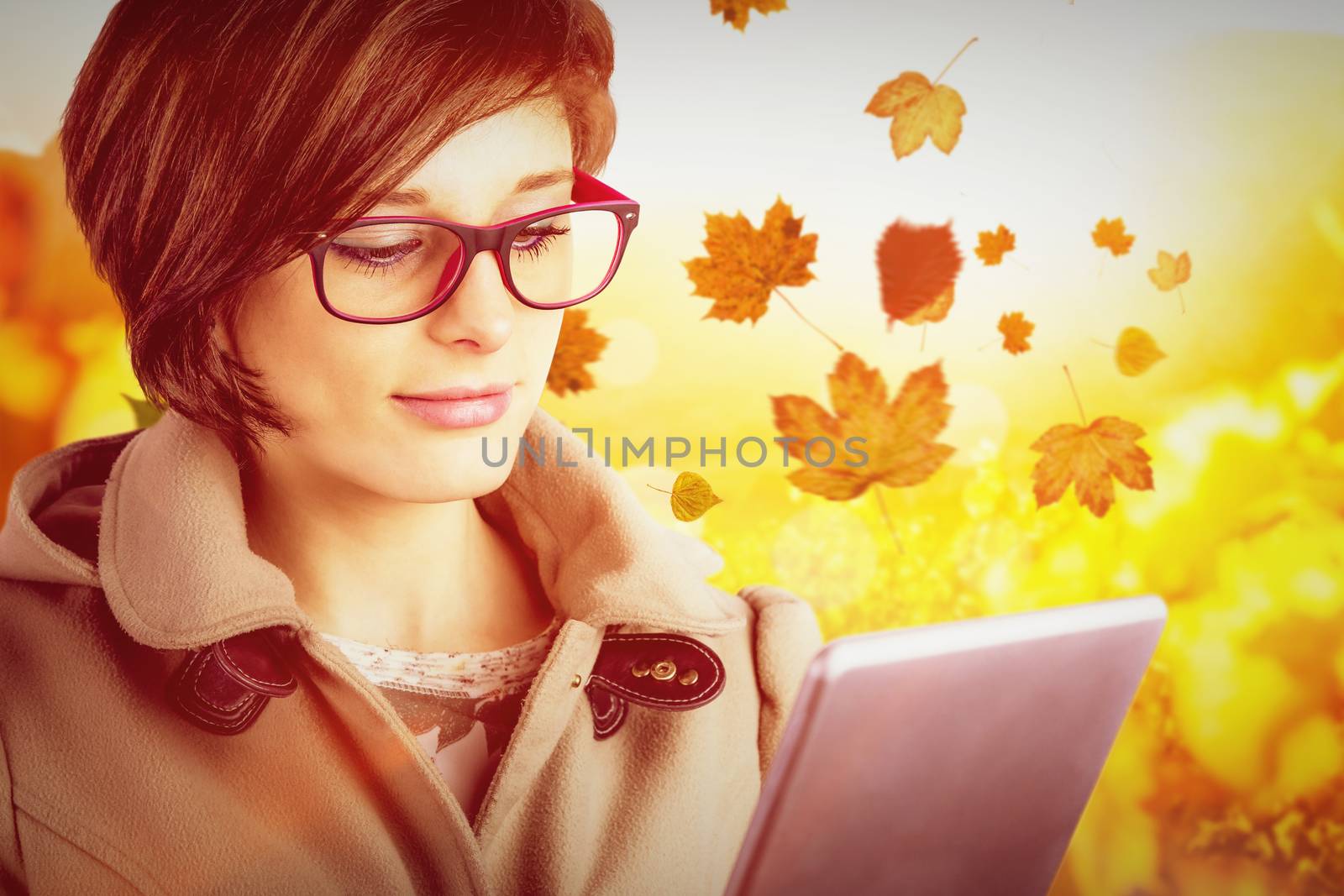 Beautiful woman in glasses using tablet computer against autumn scene
