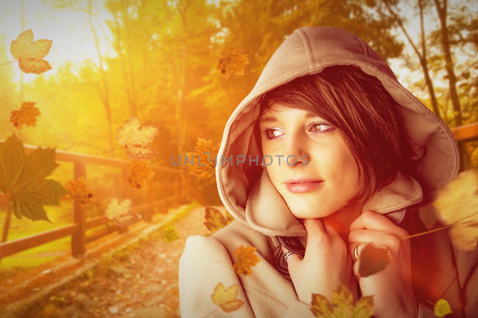 Beautiful woman wearing winter coat looking away against autumn scene