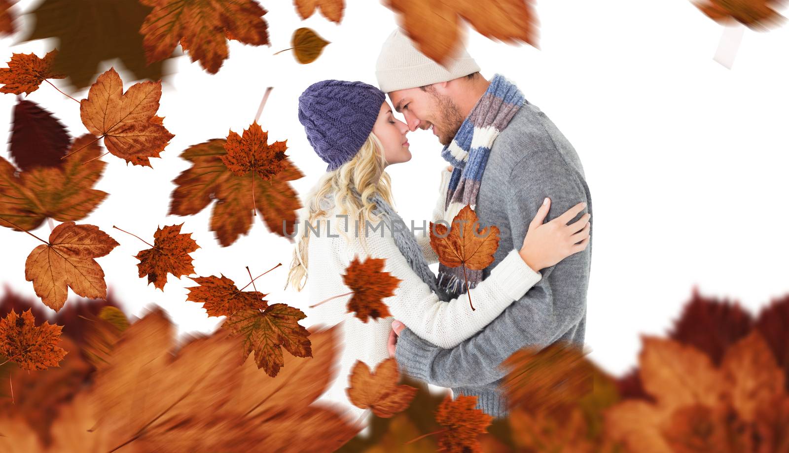 Attractive couple in winter fashion hugging against autumn leaves