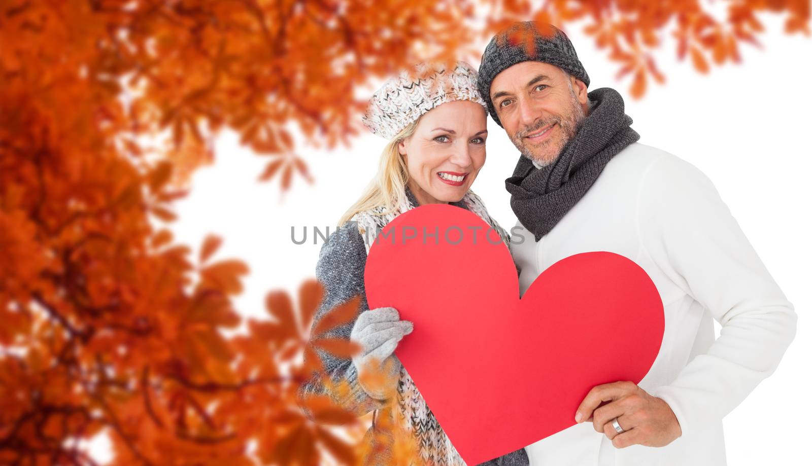 Portrait of happy couple holding heart against autumn leaves