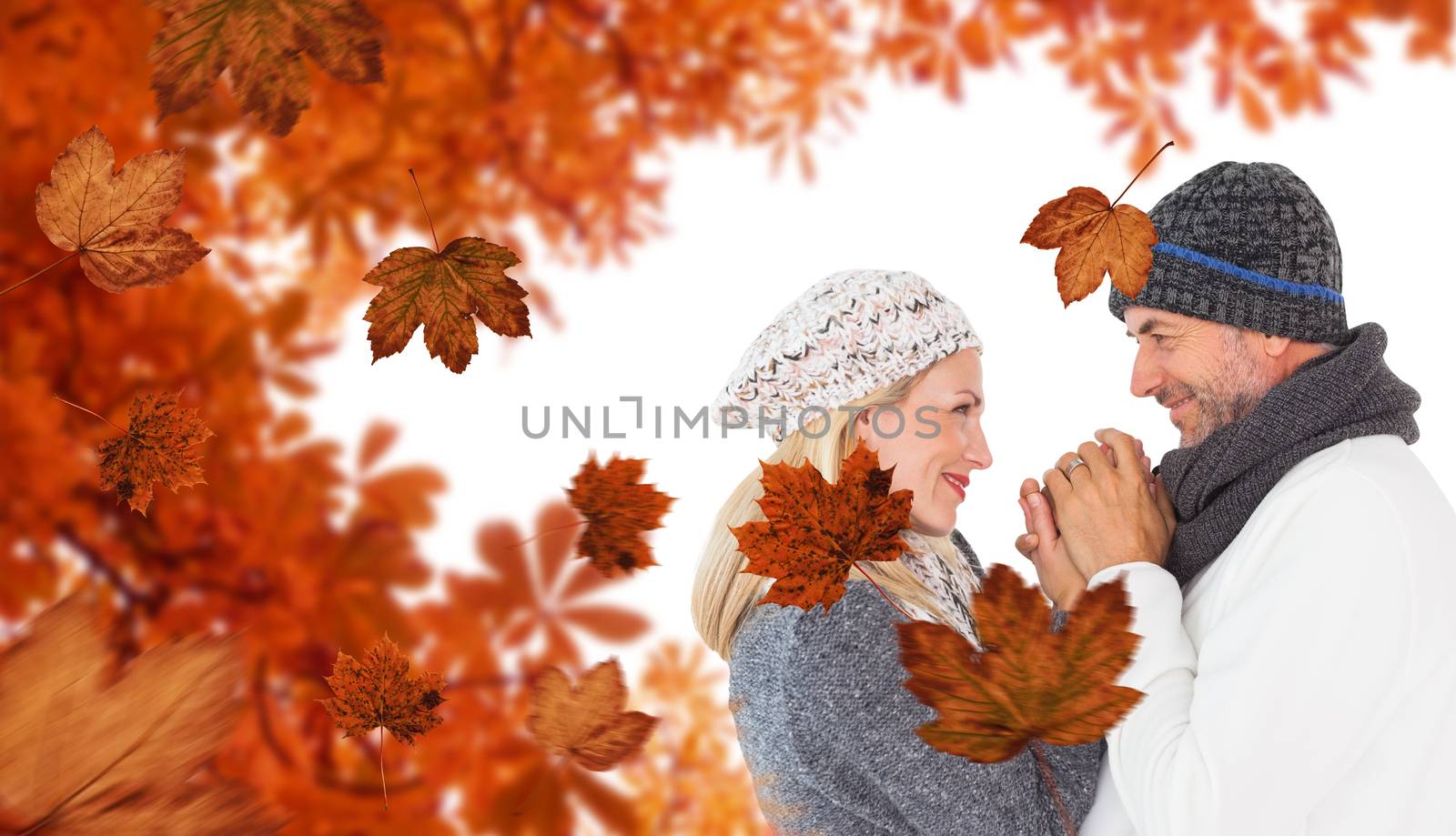Cute smiling couple holding hands against autumn leaves pattern