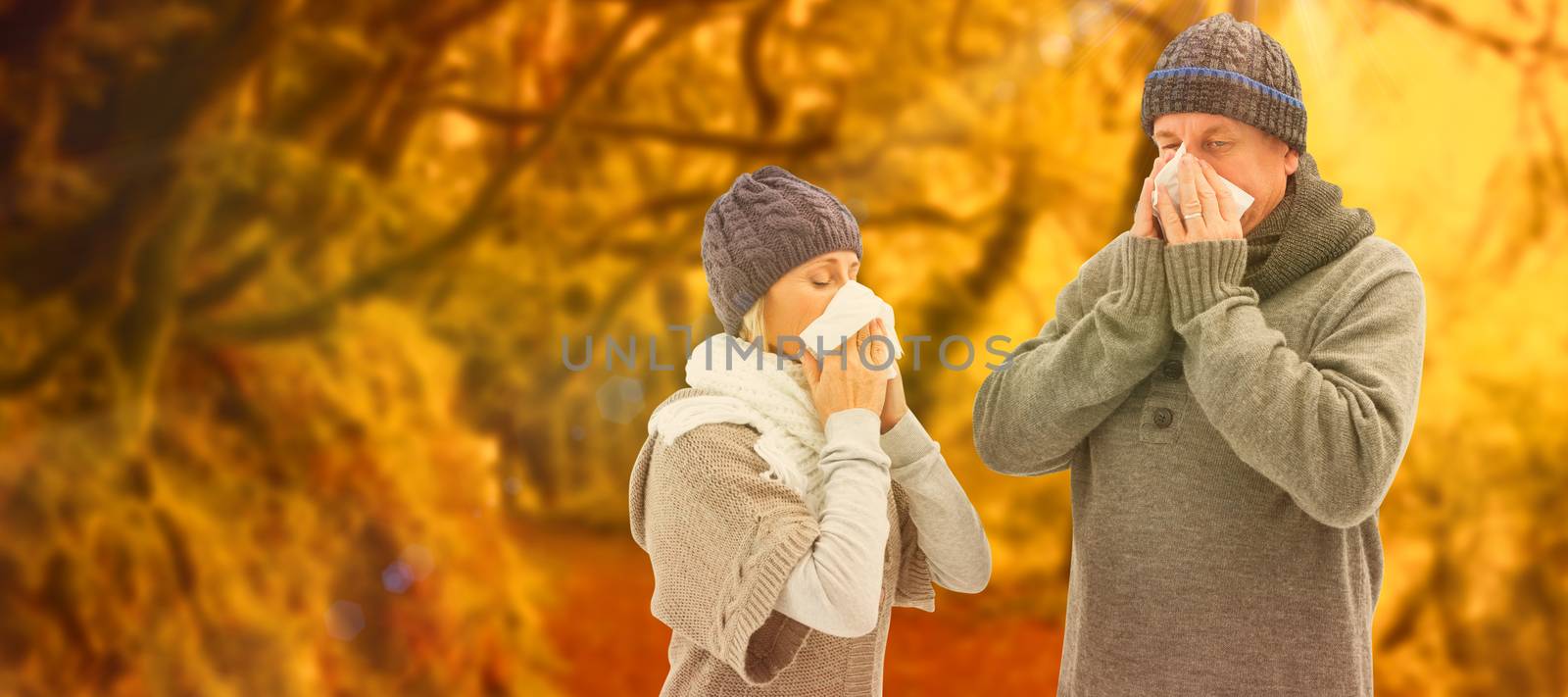 Sick mature couple blowing their noses against peaceful autumn scene in forest