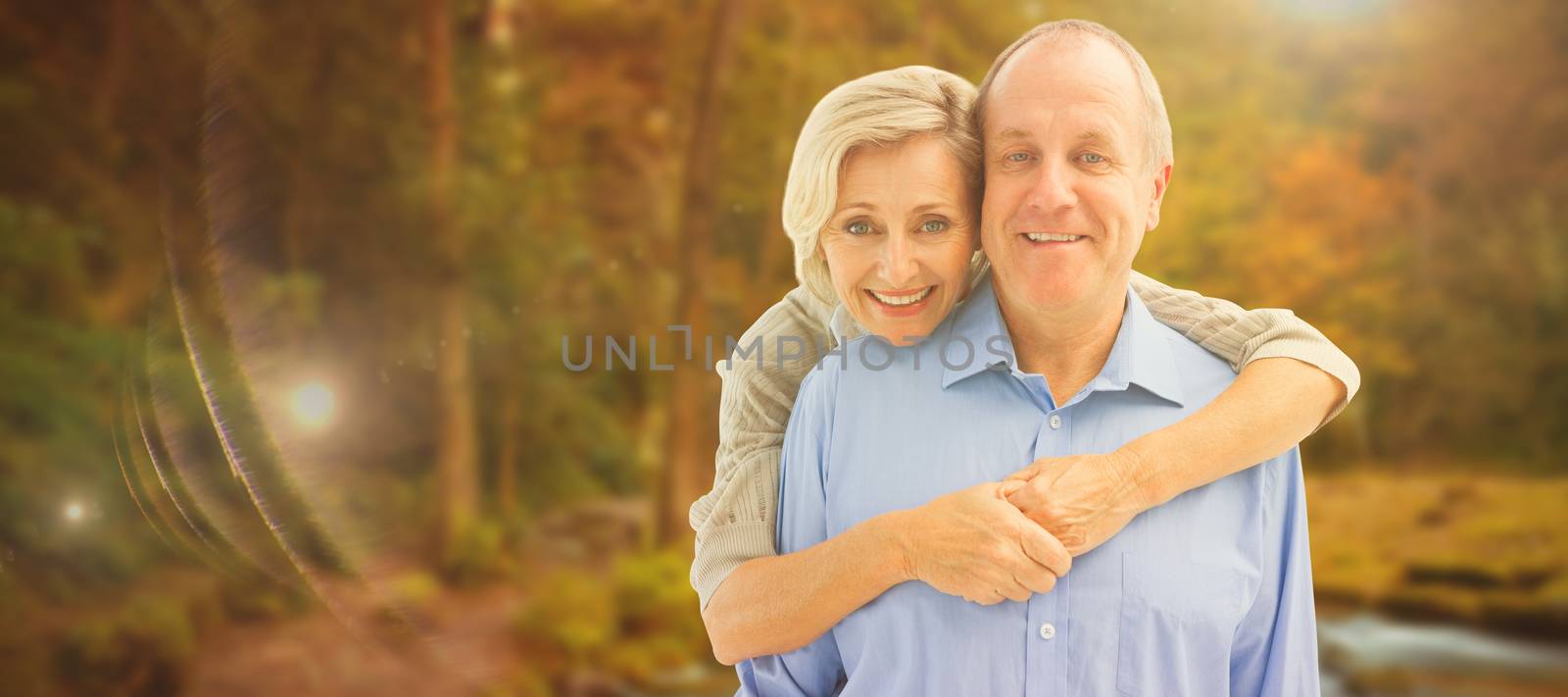 Happy mature couple embracing smiling at camera against autumn scene