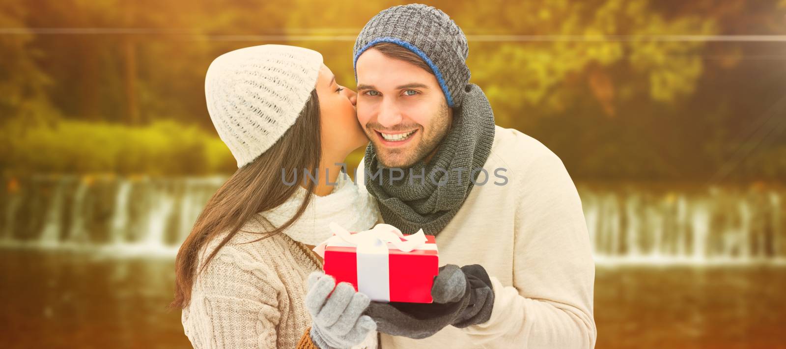 Winter couple holding gift against autumn scene