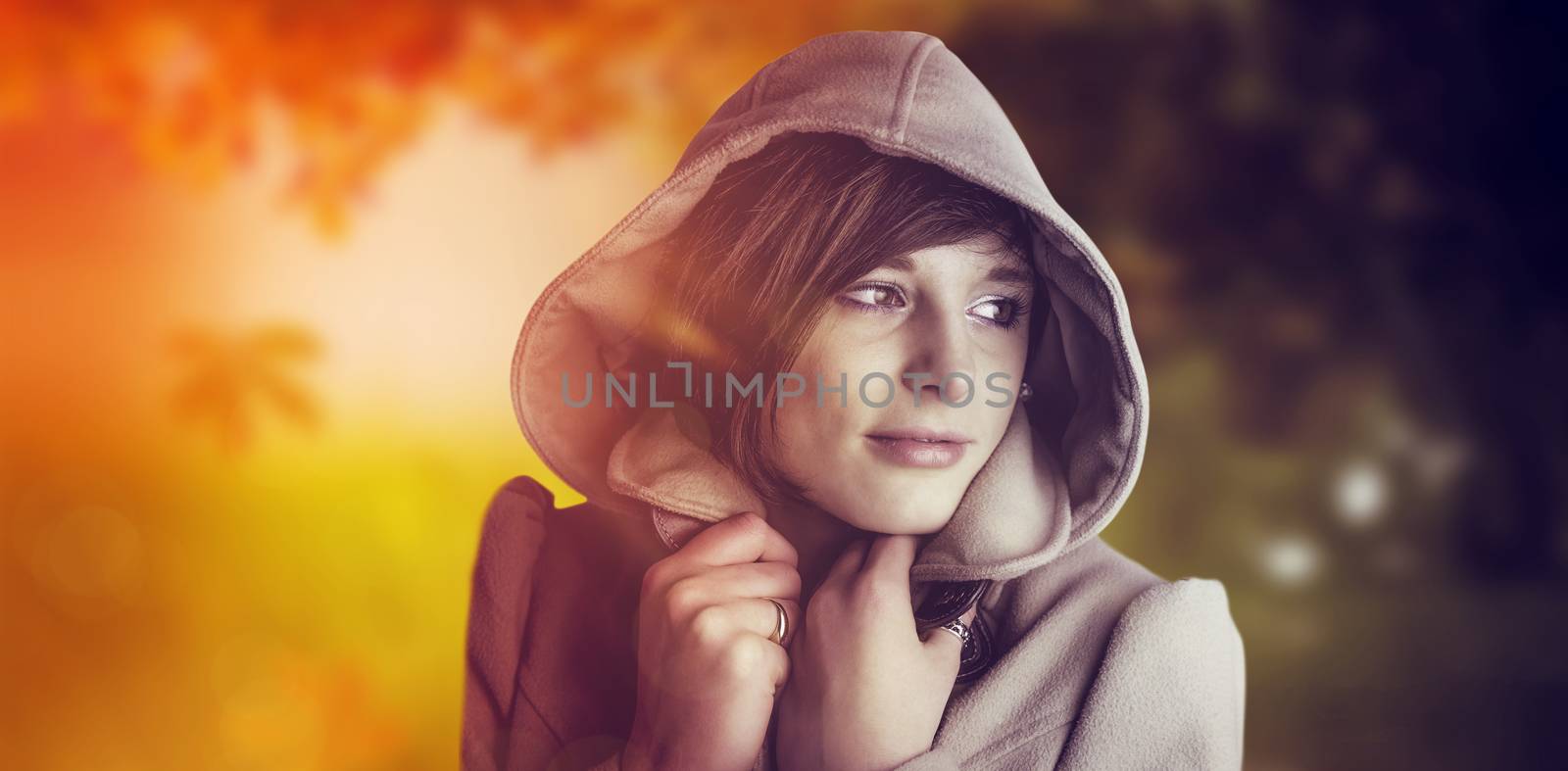 Beautiful woman wearing winter coat looking away against autumn scene