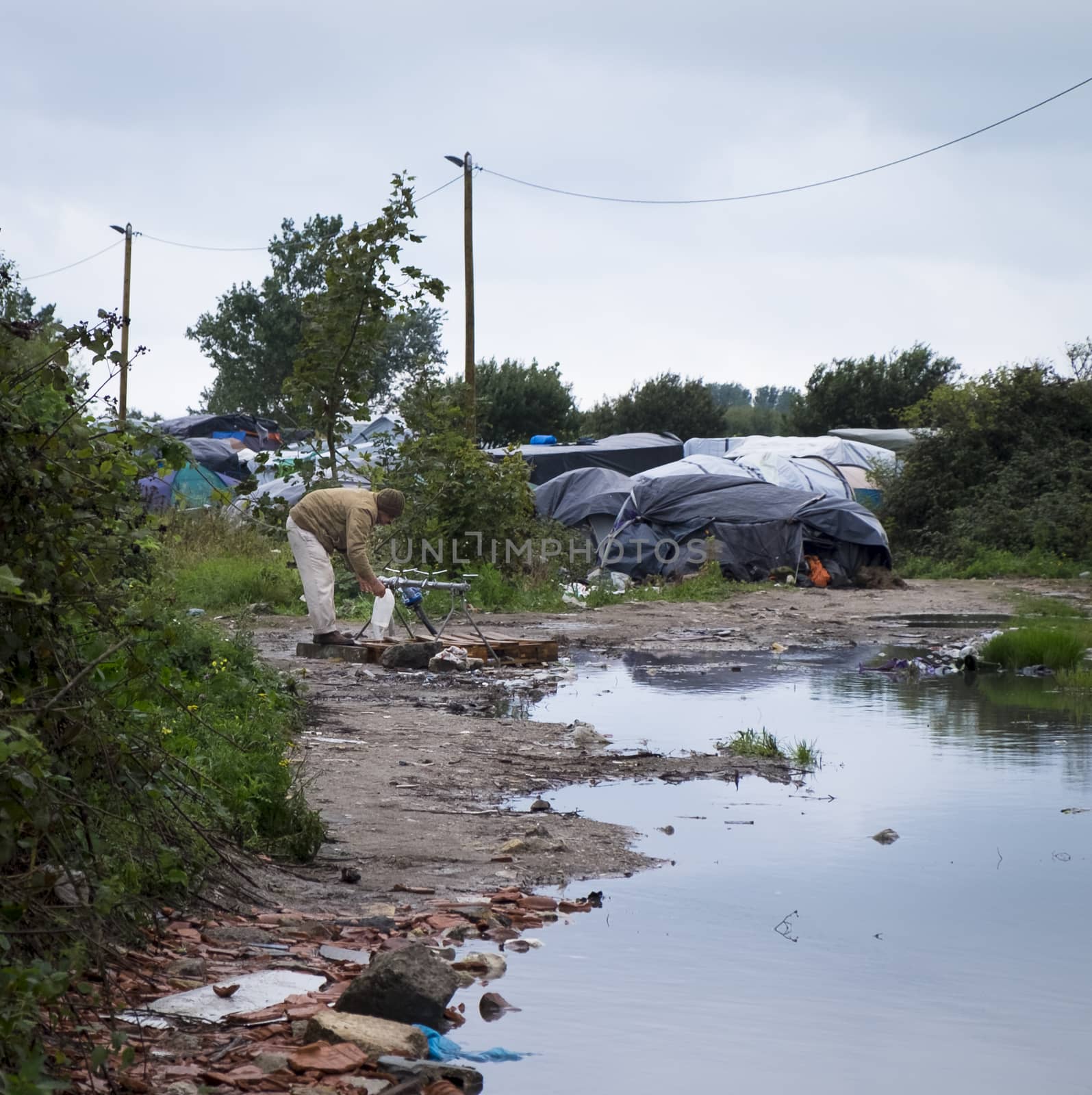 FRANCE, Calais:  A man collects water at the New Jungle refugee and migrant camp near Calais, France, on September 17, 2015.	Refugees and migrants trying to enter the UK from France are facing dropping temperatures and poor sanitation at the makeshift camp.
