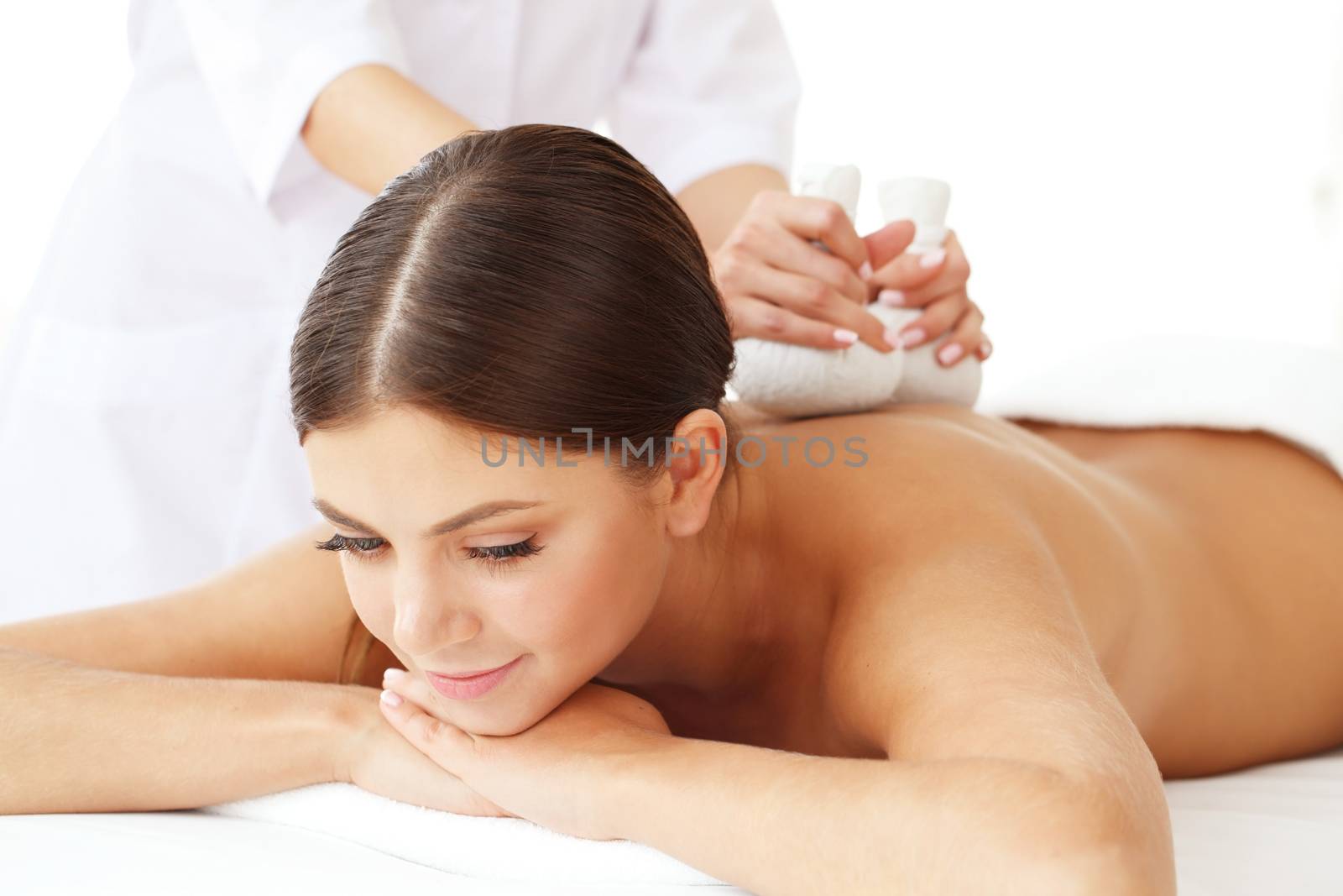 Woman in spa getting massage with herbal balls