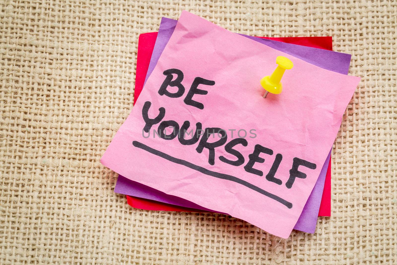 Be yourself reminder or advice on a sticky note against burlap canvas