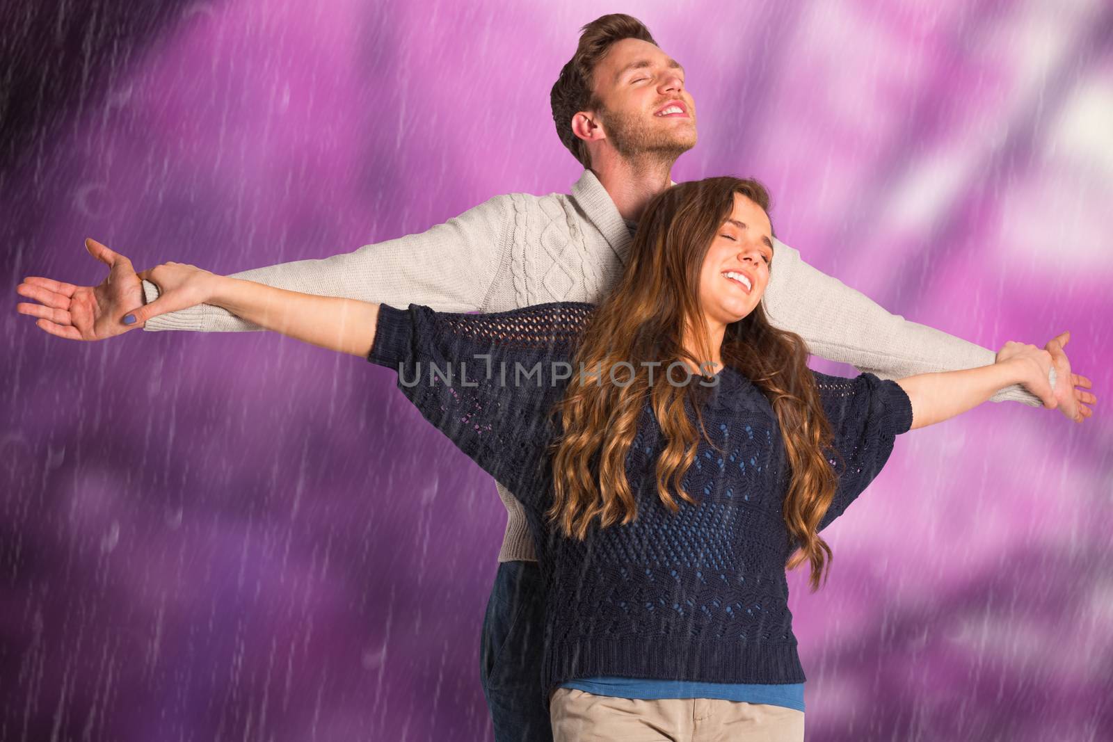 Romantic young couple with arms out against colourful forest