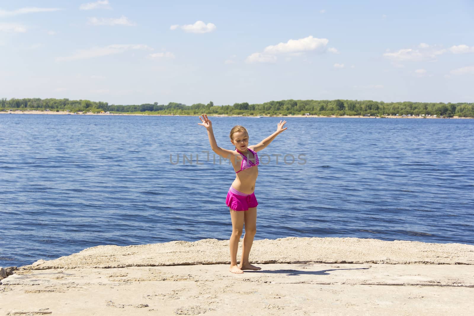 Dancing girl on the riverbank in pink swimsuit
