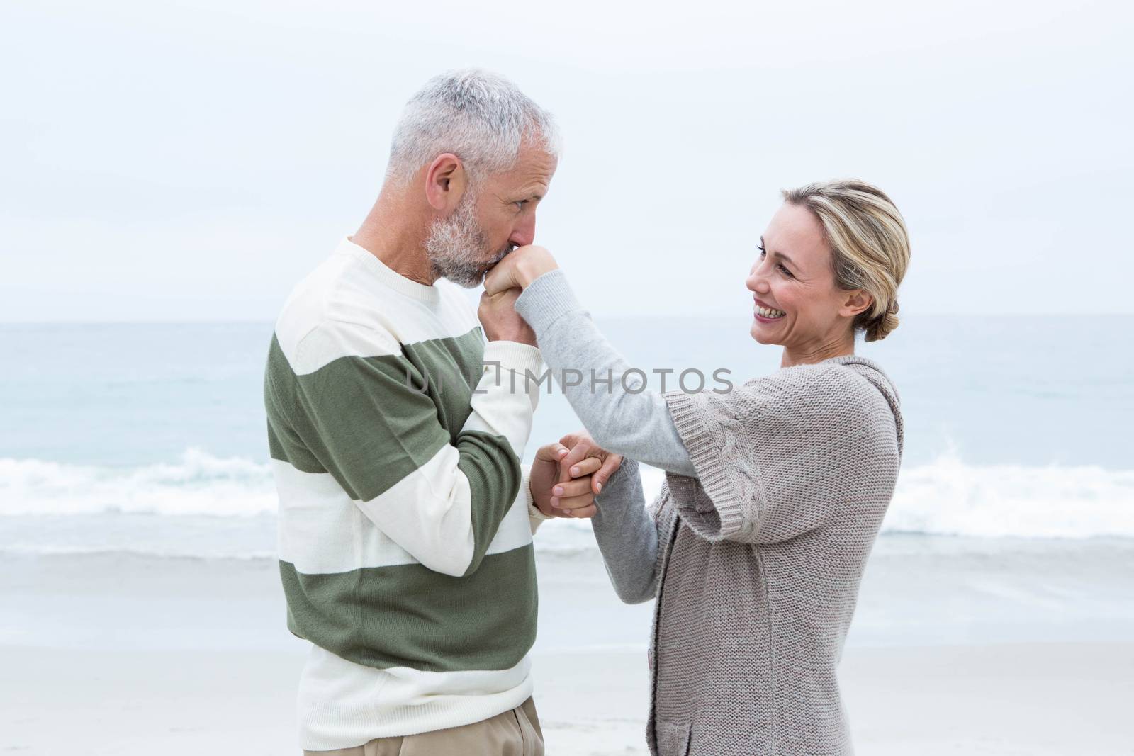 Romantic man kissing womans hand at the beach