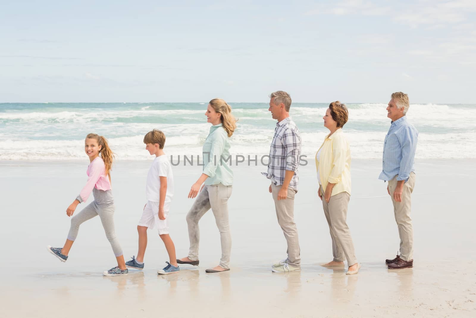 Multi generation family standing beside one another at the beach