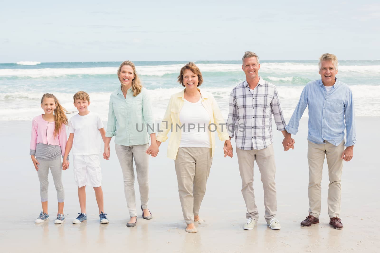 Multi generation family standing beside one another at the beach