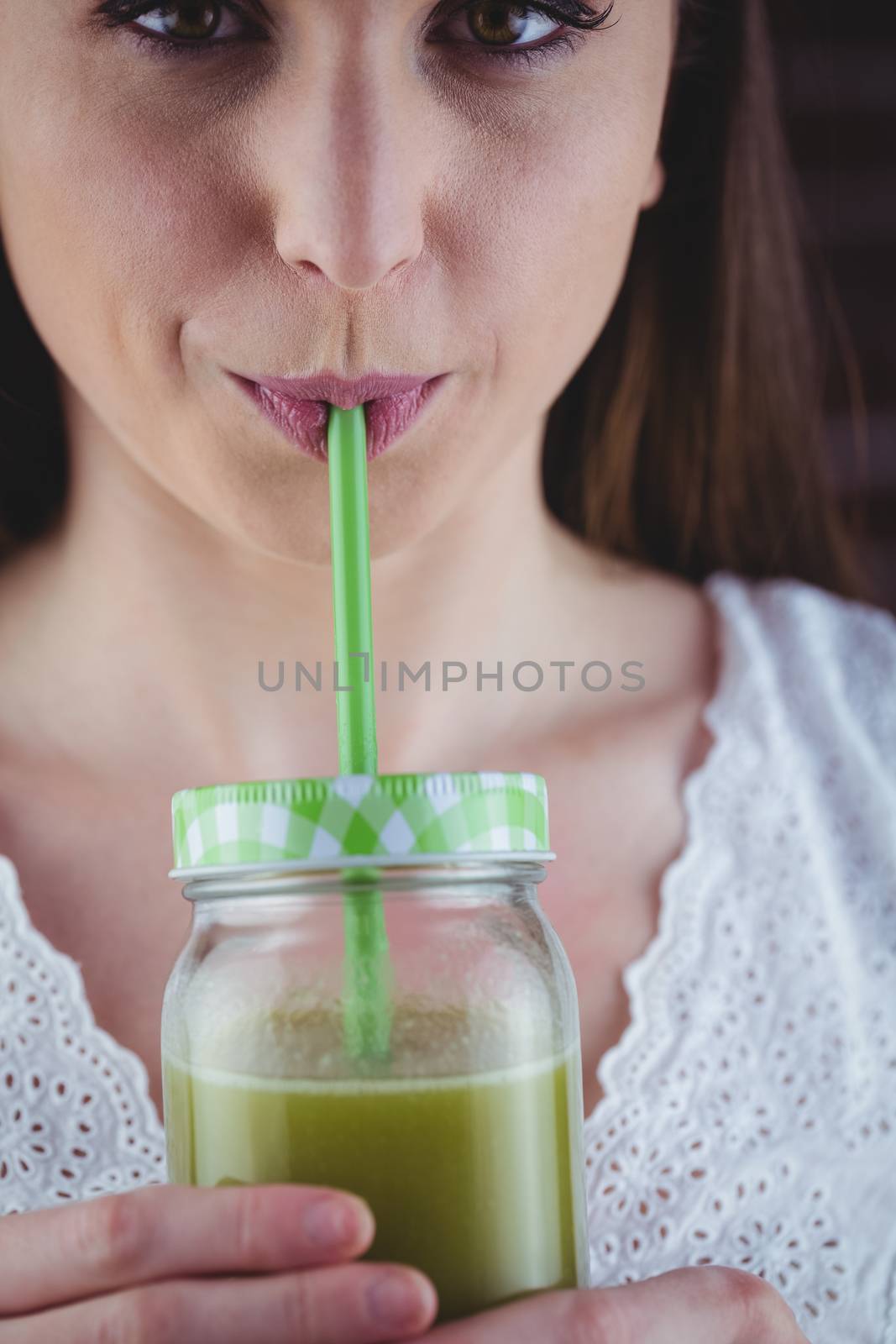 Pretty woman sipping on green juice by Wavebreakmedia